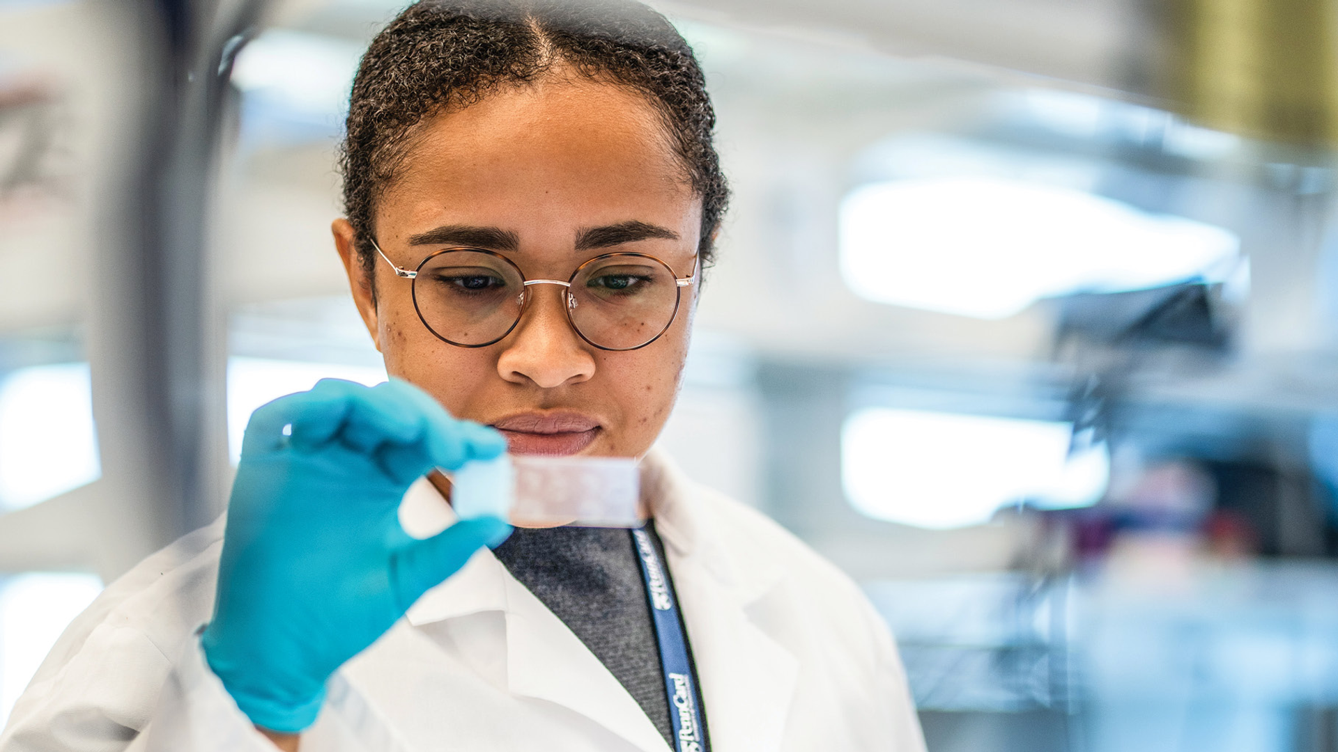 A researcher in the lab of Drew Weissman looks at a microscope slide