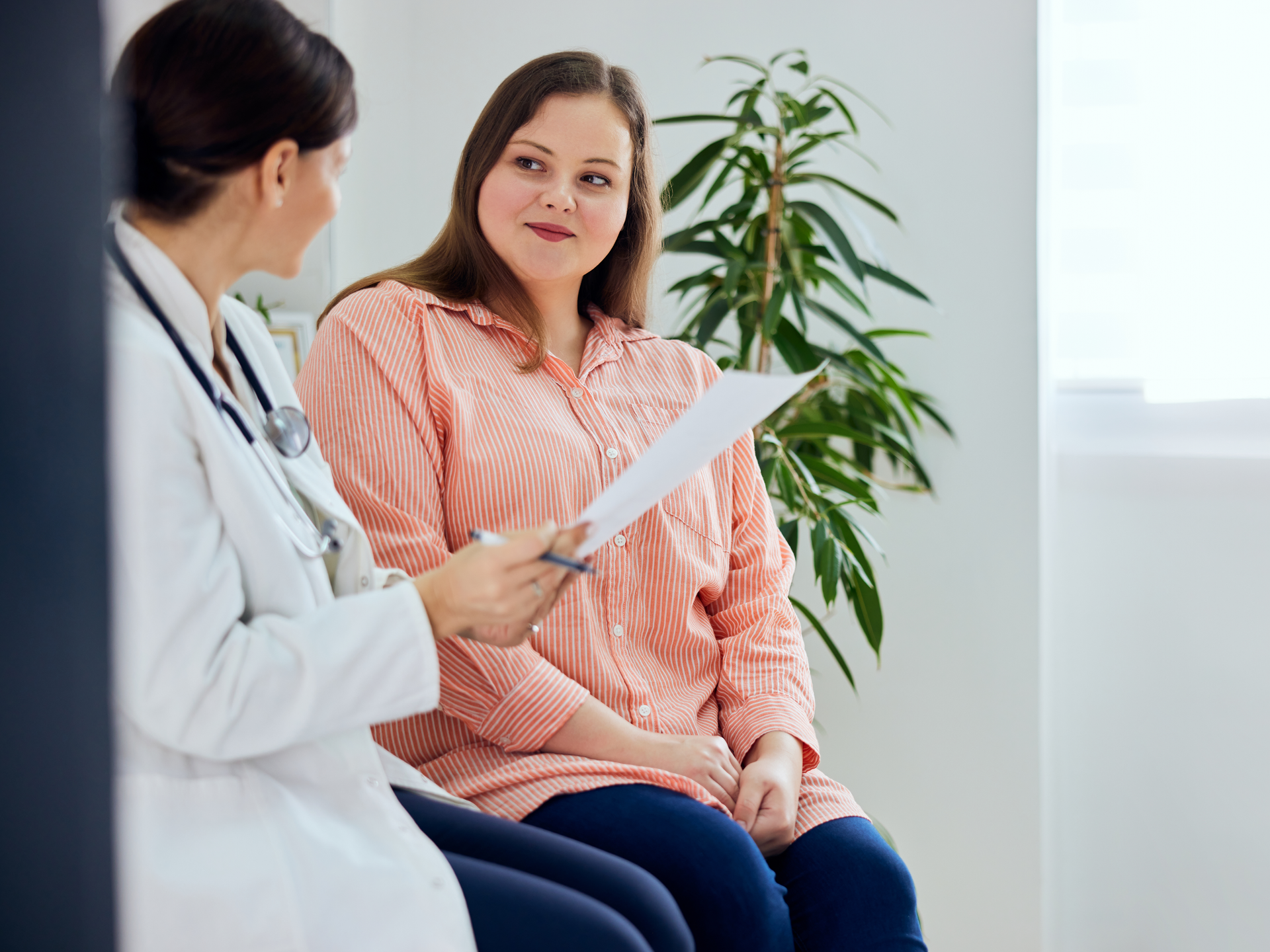 A smiling plus-size woman consulting with doctor
