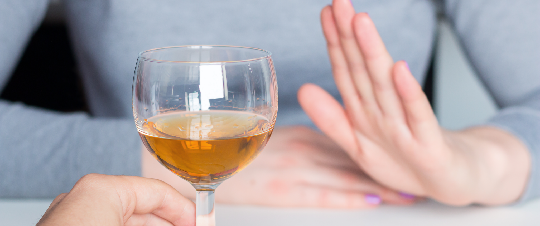 Person holding up hand by glass of wine