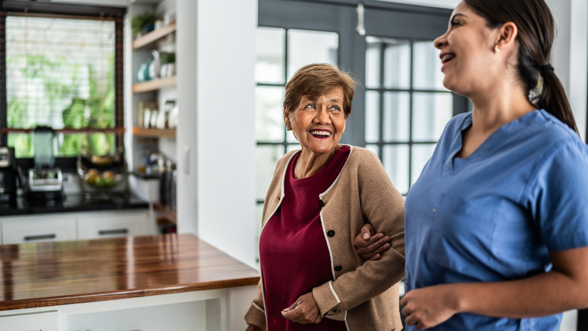 Home caregiver helping senior woman to walk at house