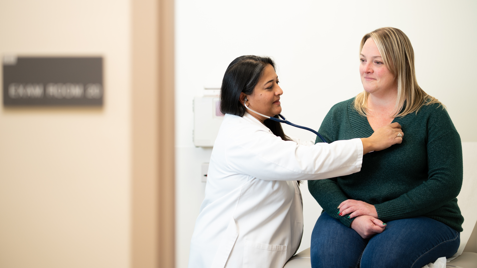 Aileen John puts a stethoscope to a patient’s chest.