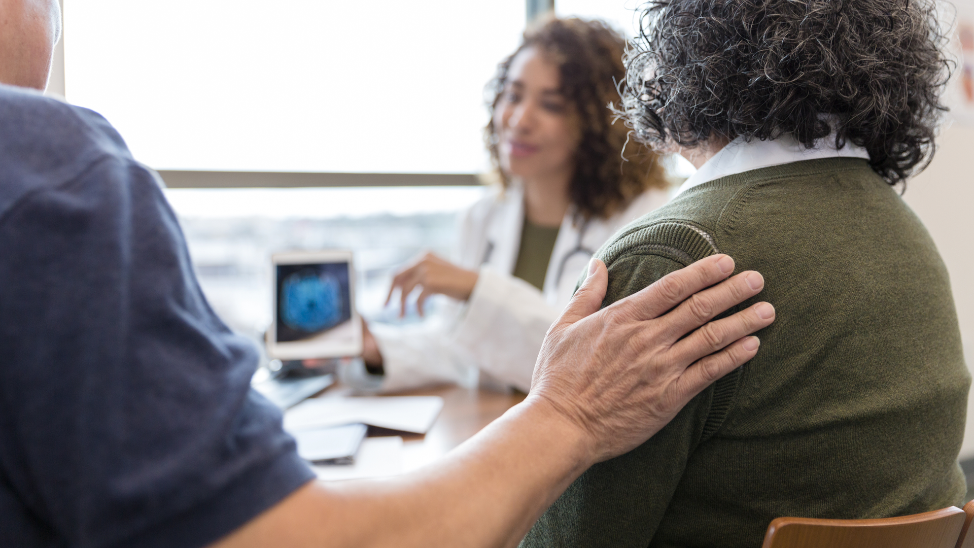 Husband comforts wife during appointment with neurologist
