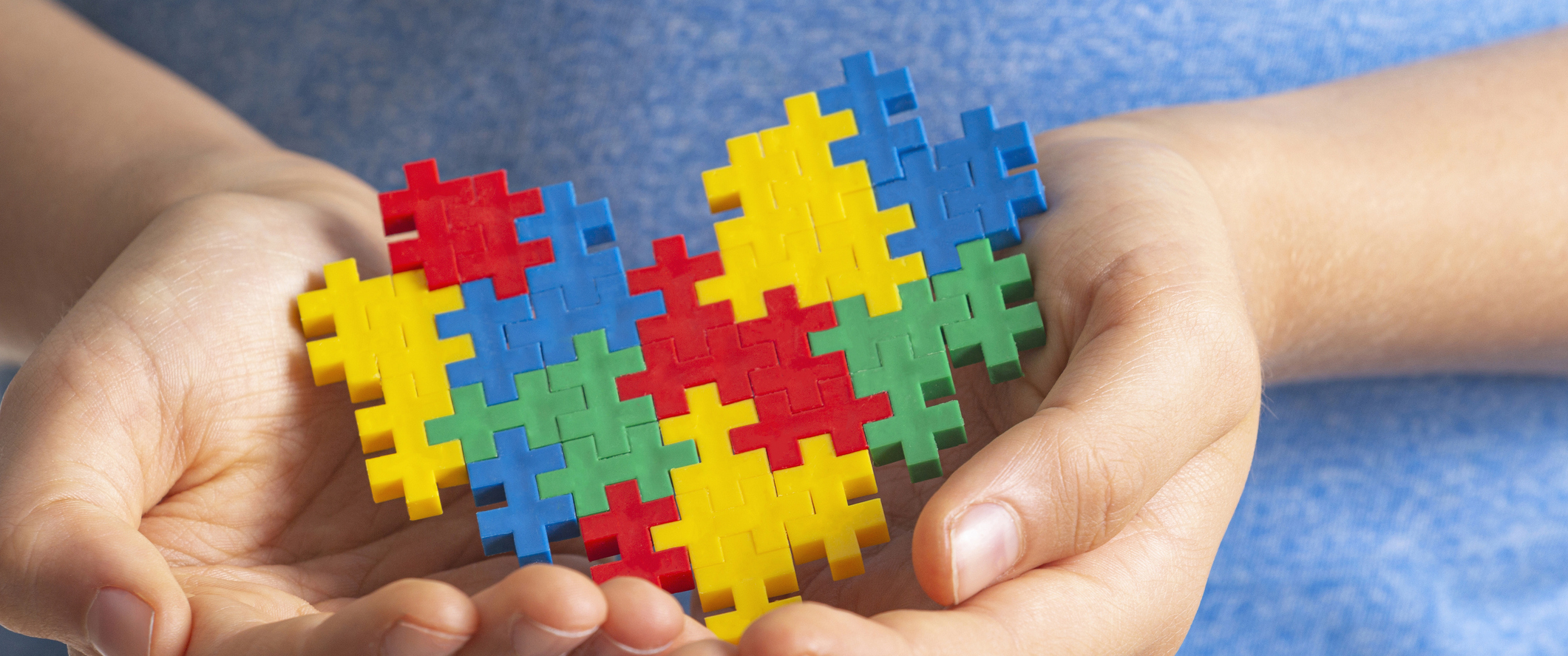 A child’s hands holding a colorful puzzle shaped like a heart