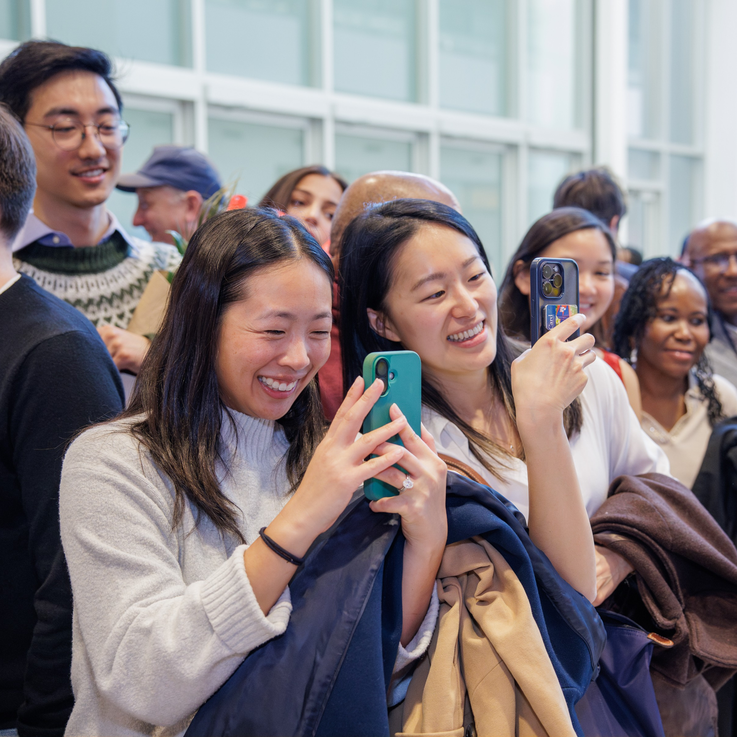 Two smiling women have their phones out to capture the Match Day 2026 celebration