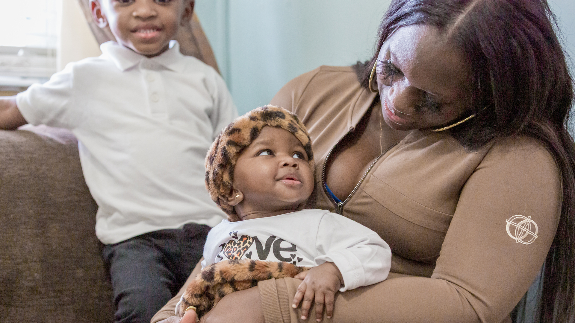 Talicia Williams cuddles her baby girl while her son smiles in the background.