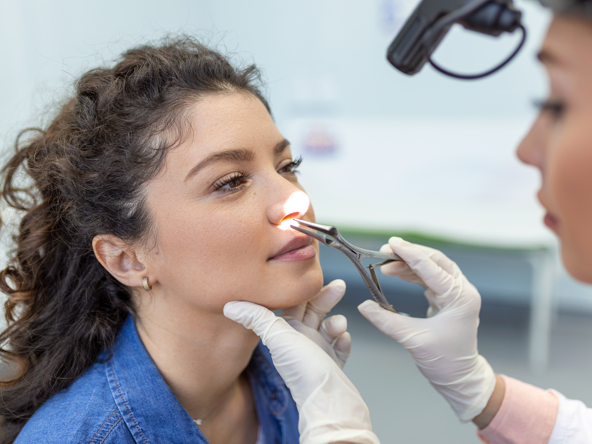 Otorhinolaryngologist checking patient's nose with otoscope