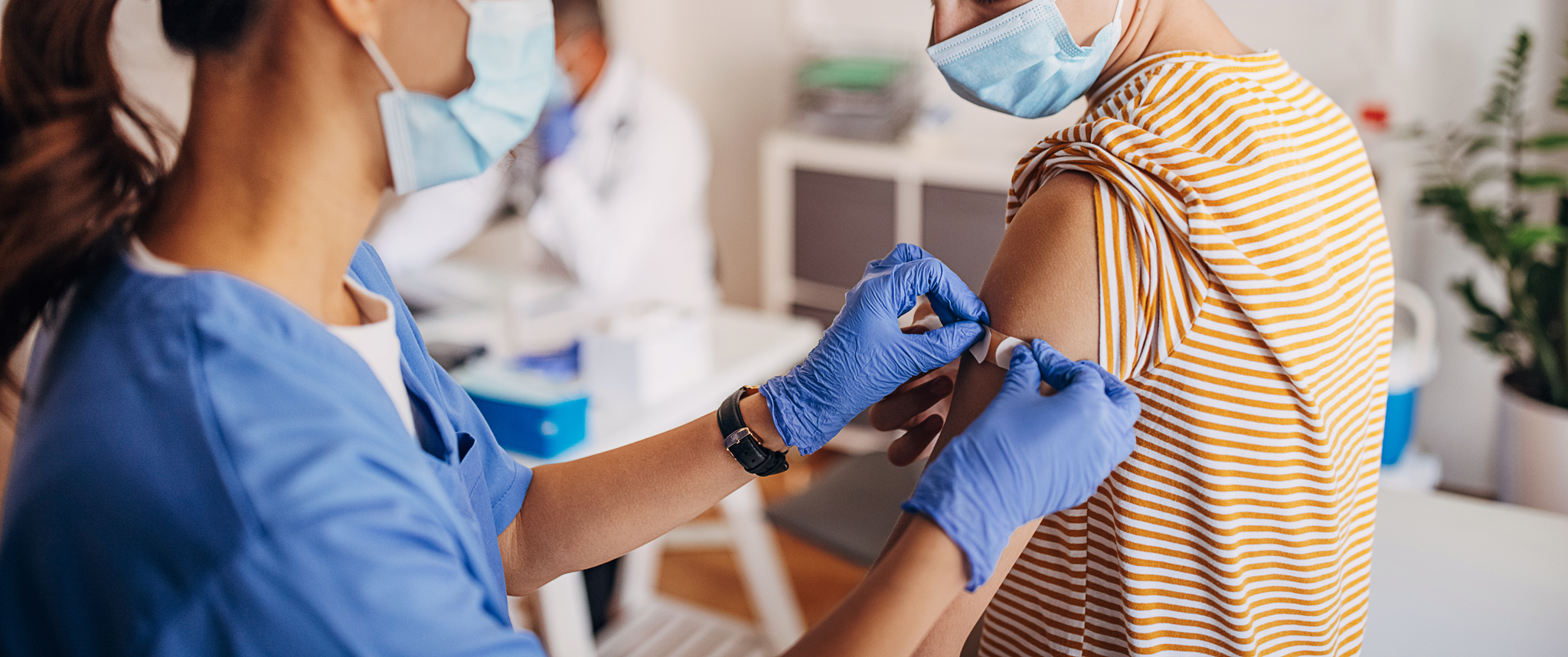 Nurse puts adhesive bandage on patient's arm after covid-19 vaccination
