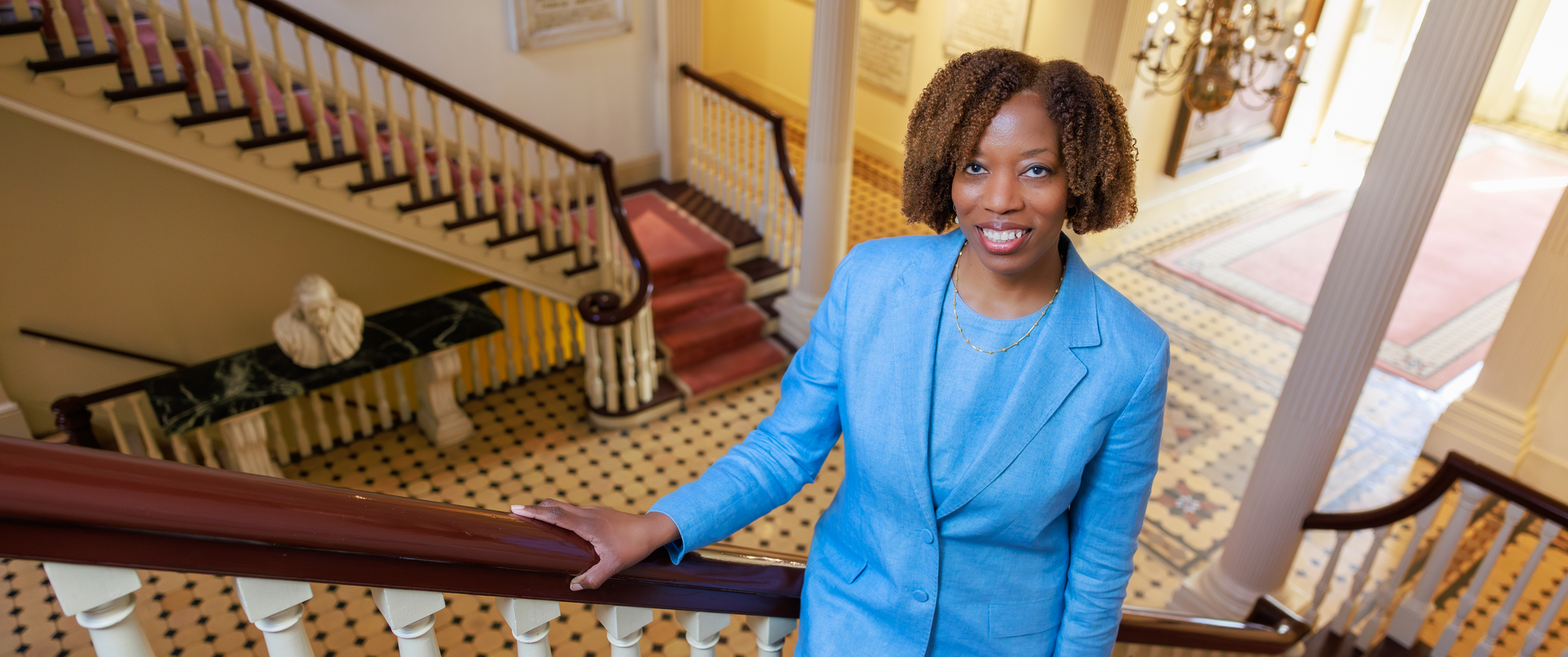 Alicia Gresham stands on a staircase in a historic building of Pennsylvania Hospital