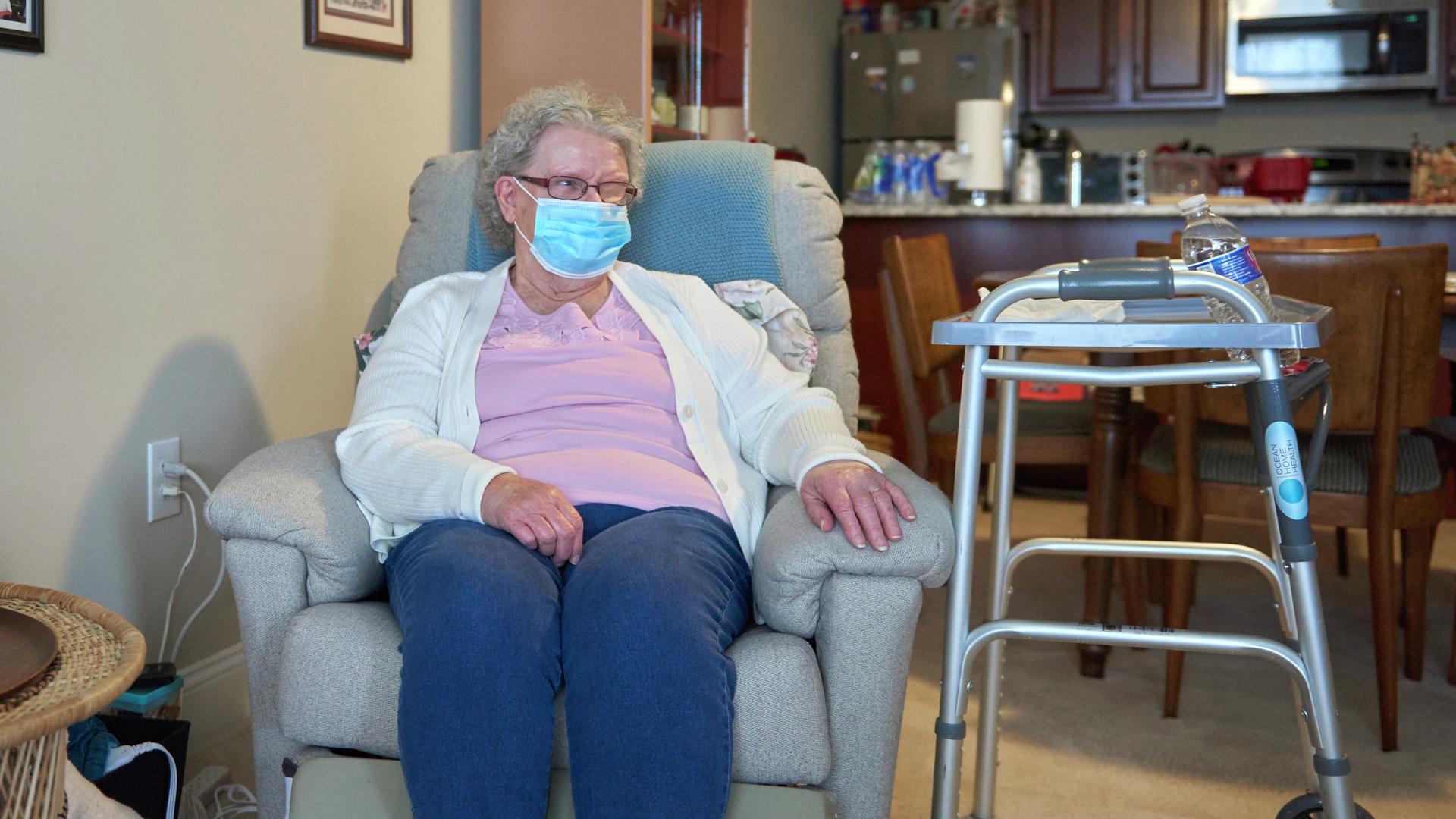 Peggy Reed, a senior woman, sits in a recliner chair with a walker at her side