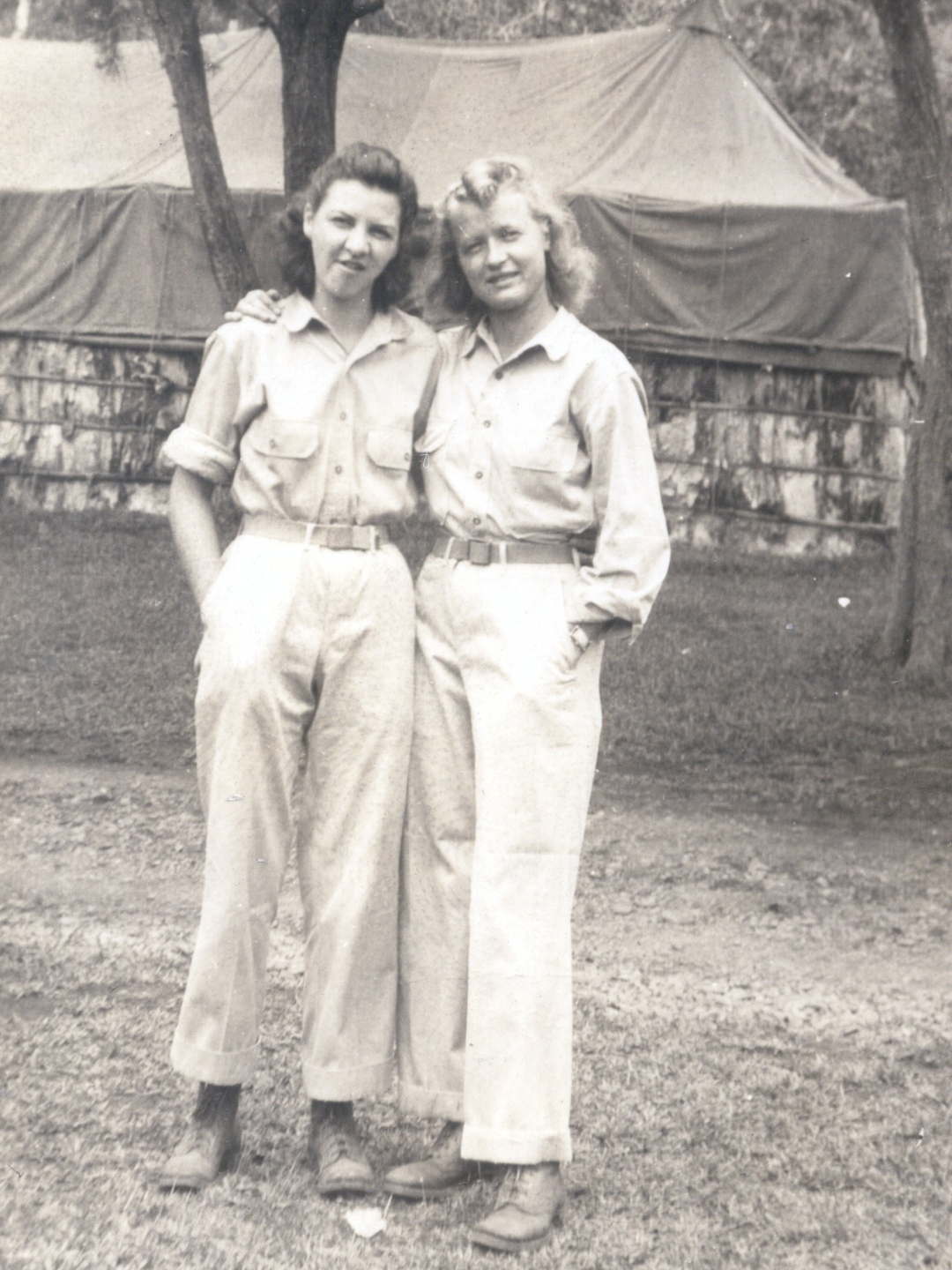 Old photo of two women wearing white shirts and trousers, serving as nurses during World War II.