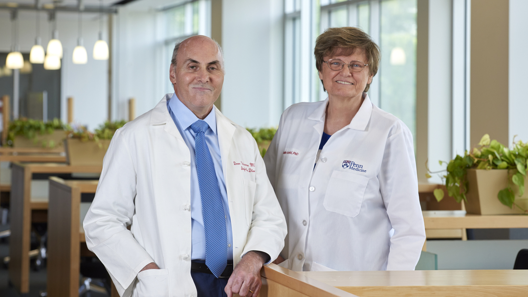 Drew Weissman and Katalin Kariko, smiling, wearing white coats