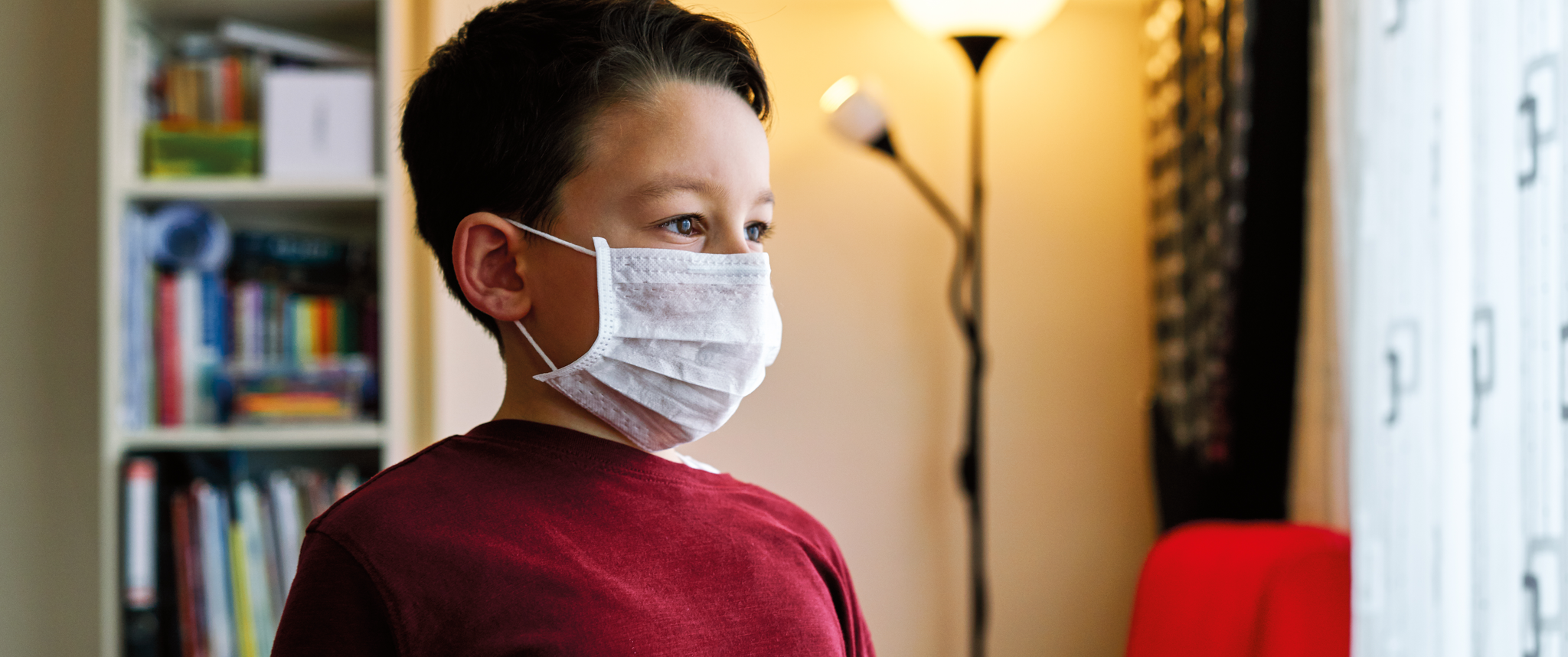 A child wears a medical mask at home