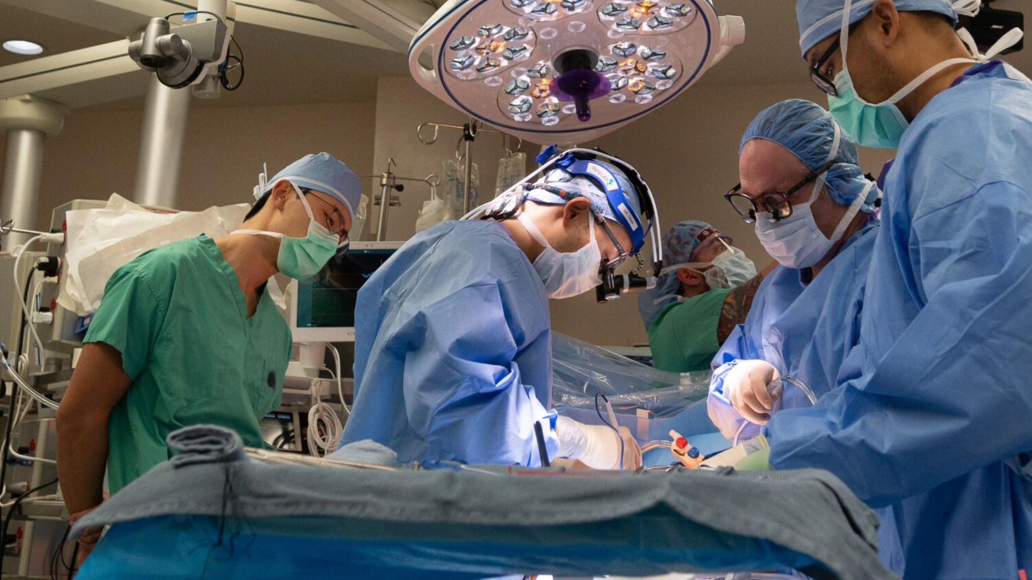  In an operating room, a team of surgeons perform minimally invasive heart surgery.