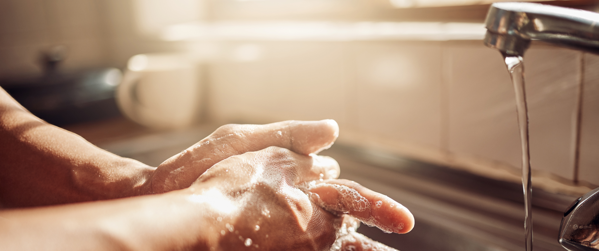 Person washing hands in kitchen sink