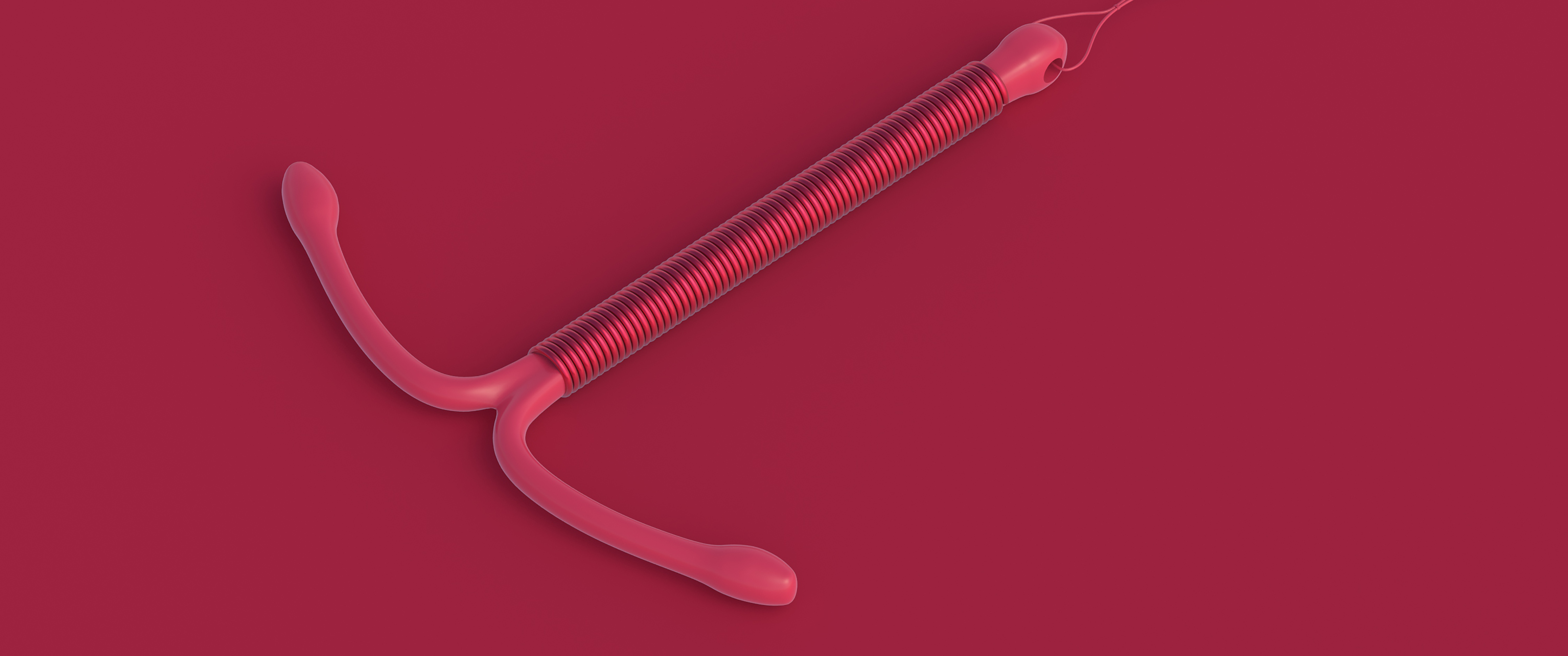 An IUD device laying on a dark red background.