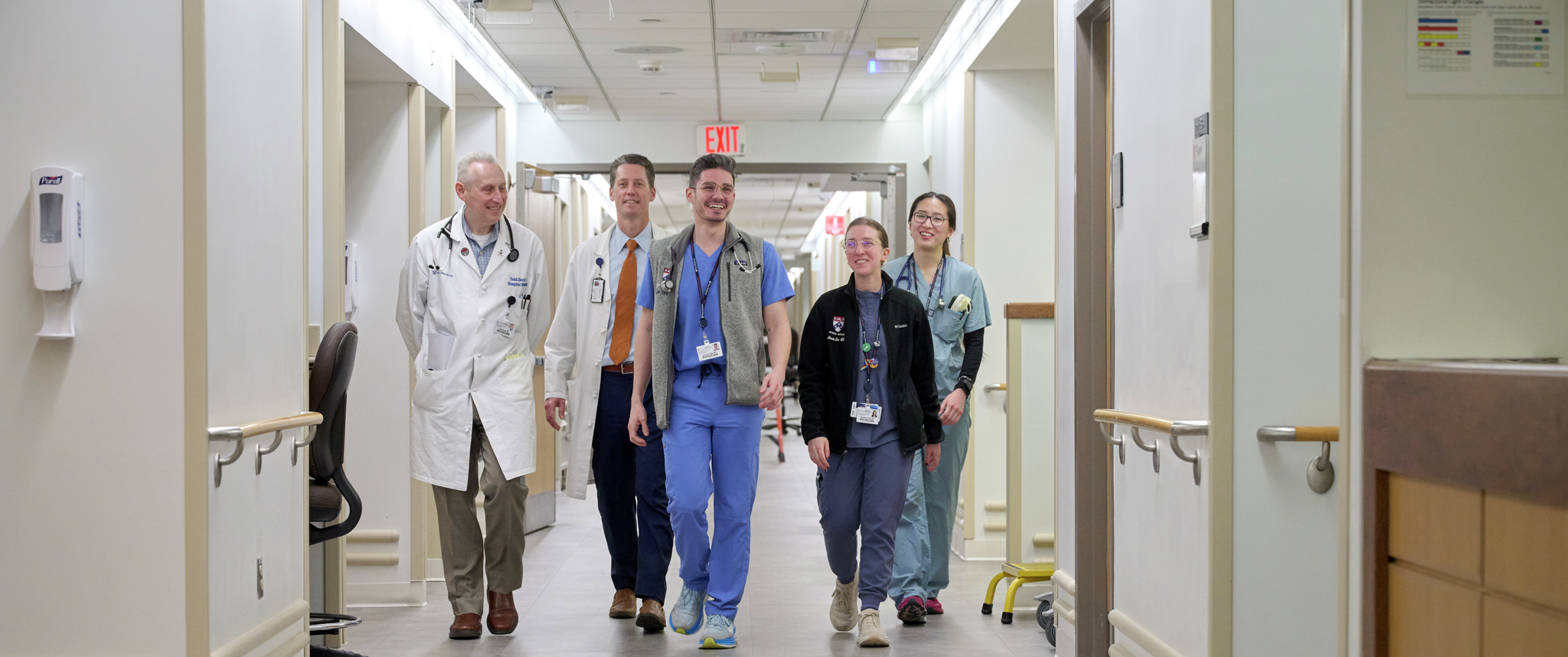 A group of physicians including Todd Hecht and Ryan Greysen walk down a hospital hallway