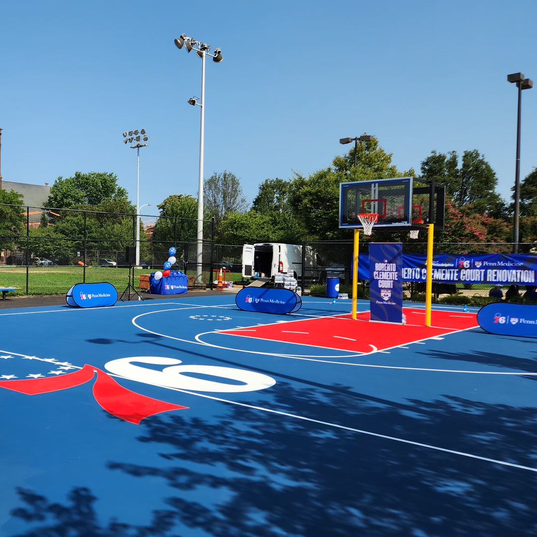 A large, clean community basketball court with 76ers logo at center
