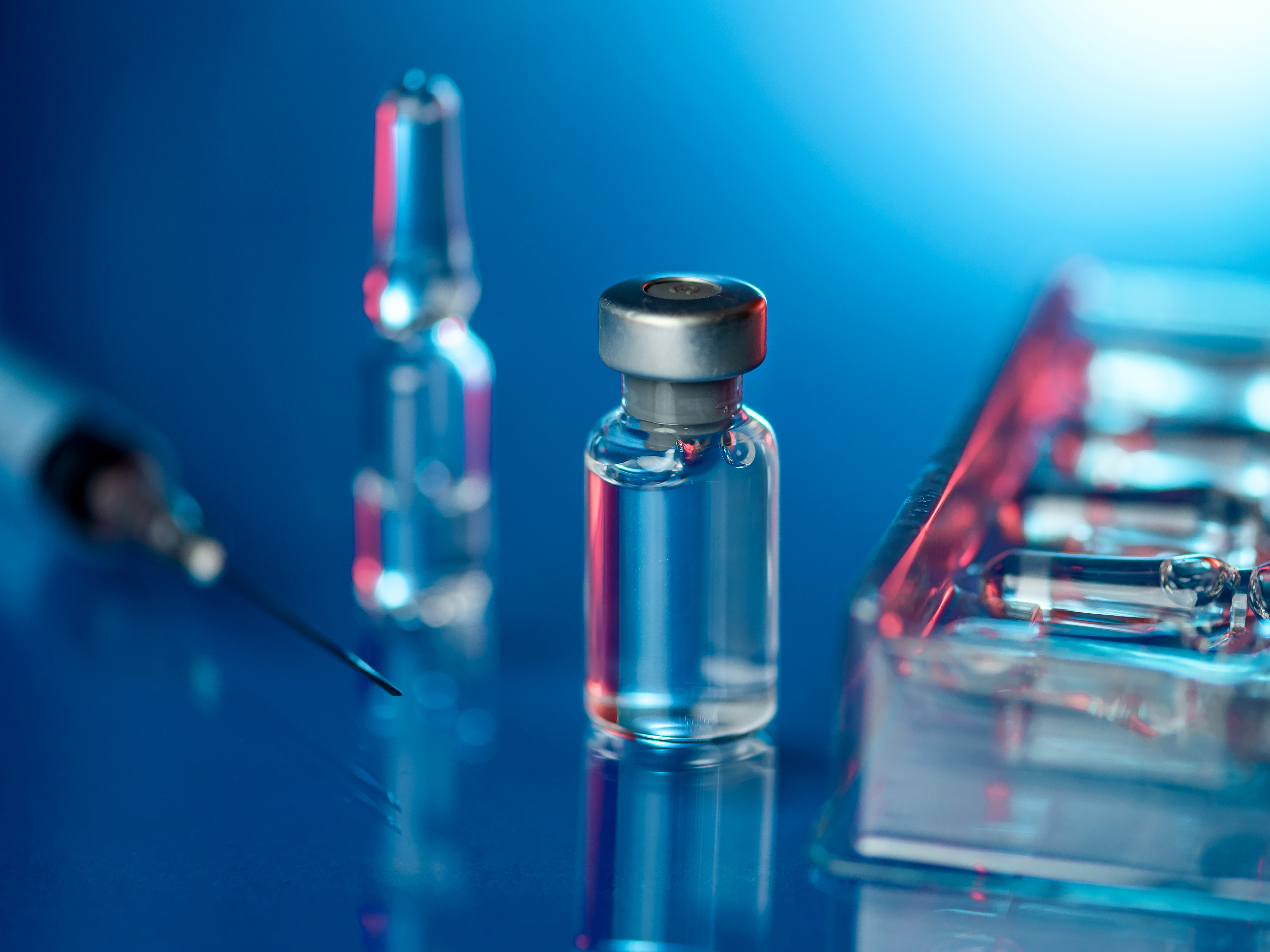 Close up shot of vaccines - glass bottles, ampules and syringe with needle