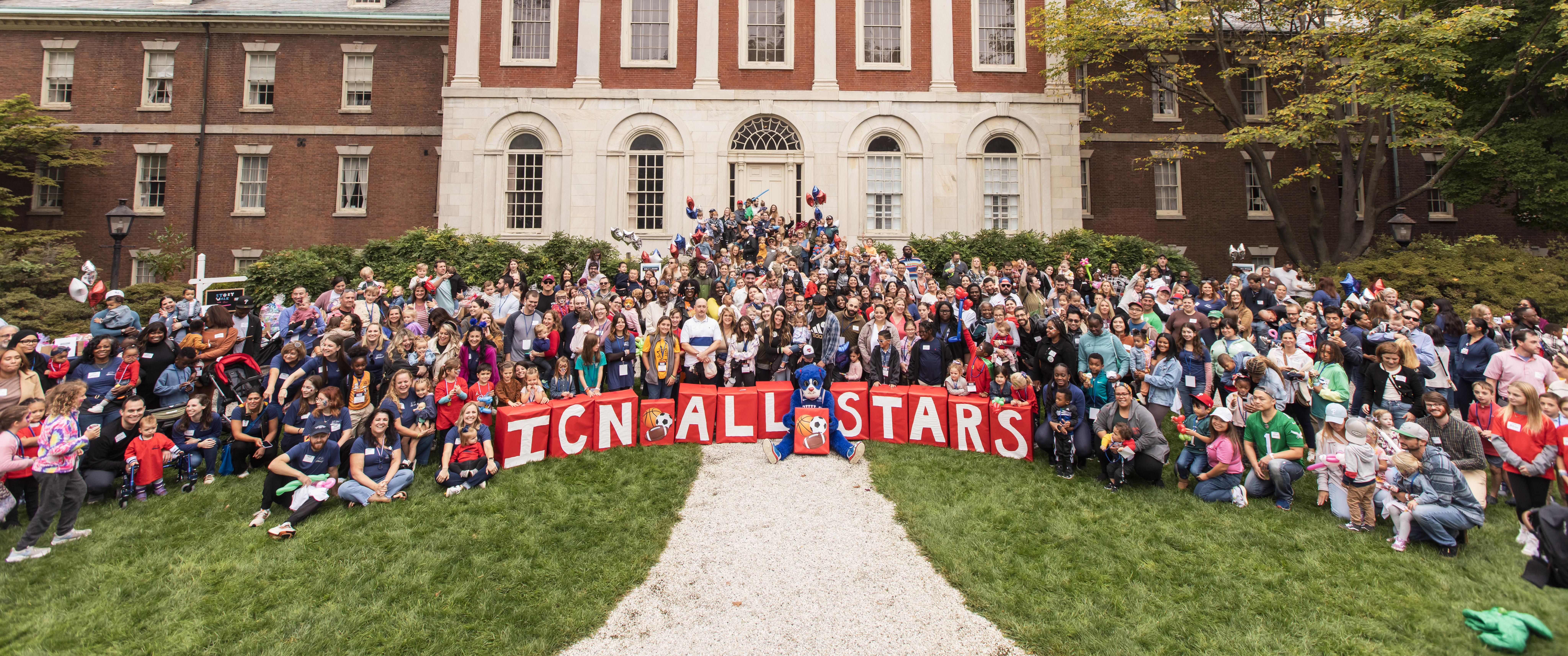 A wide group photo of more than 100 attendees, babies, children and adults, outside of Pennsylvania Hospital, with big blocks spelling out "ICN All Stars"