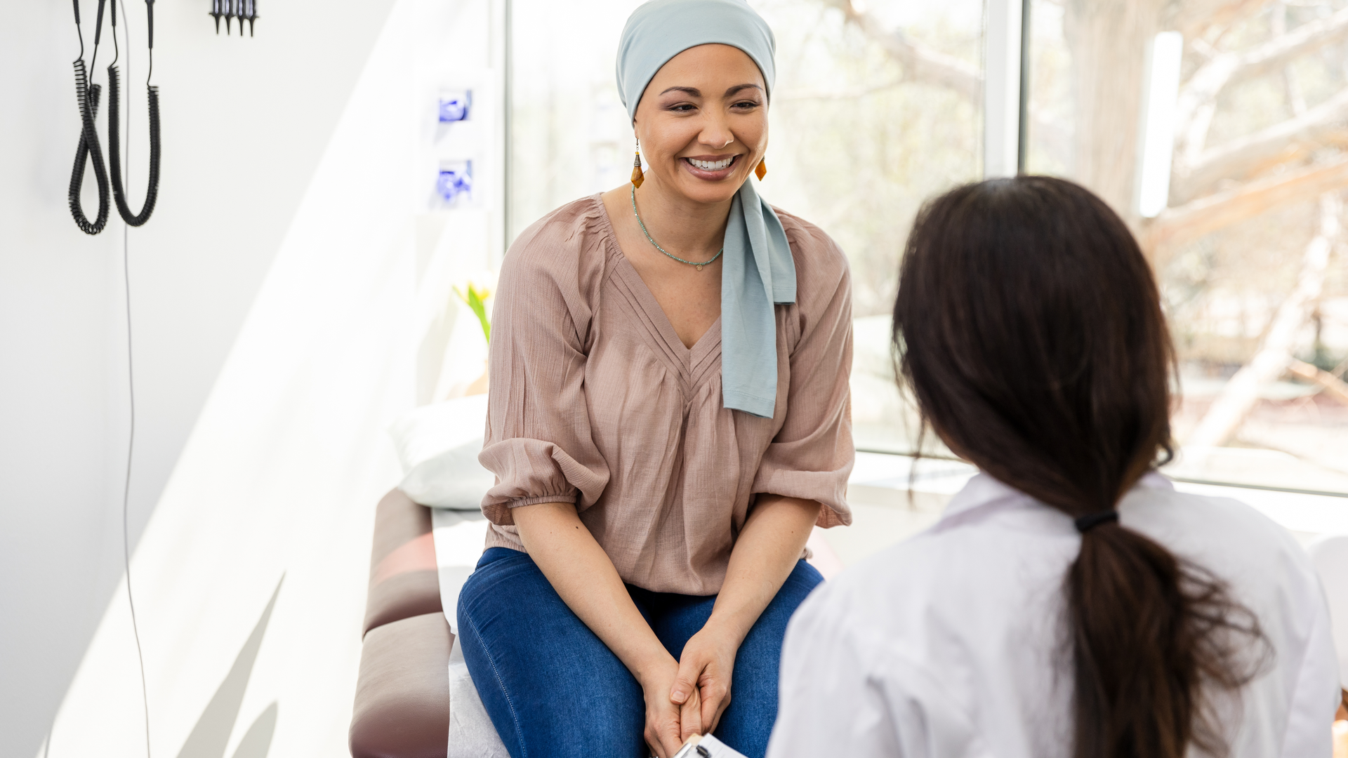  Female oncology patient smiles at unrecognizable female doctor