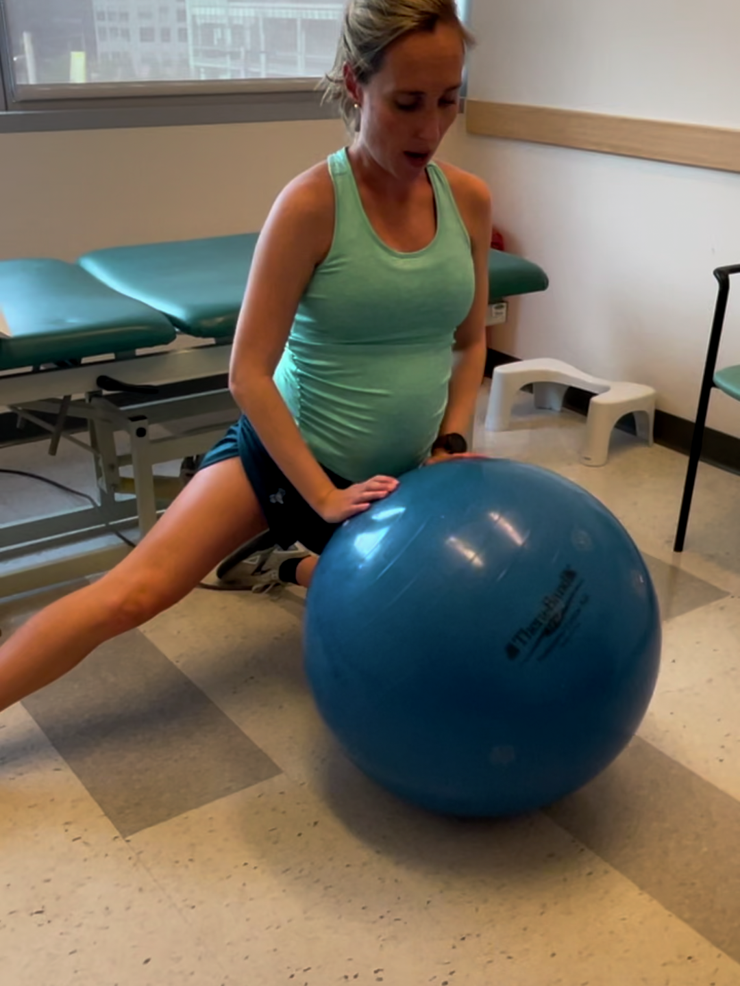 Katie Florio does a hip stretching exercise on the floor with a balance ball
