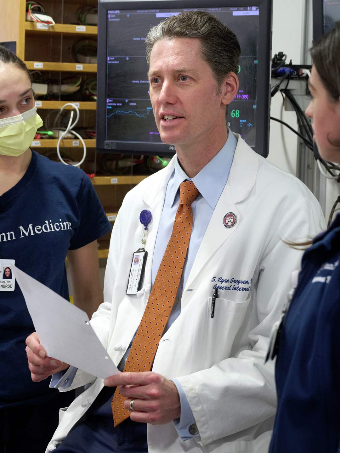 S. Ryan Greysen stands talking with a group of three nurses
