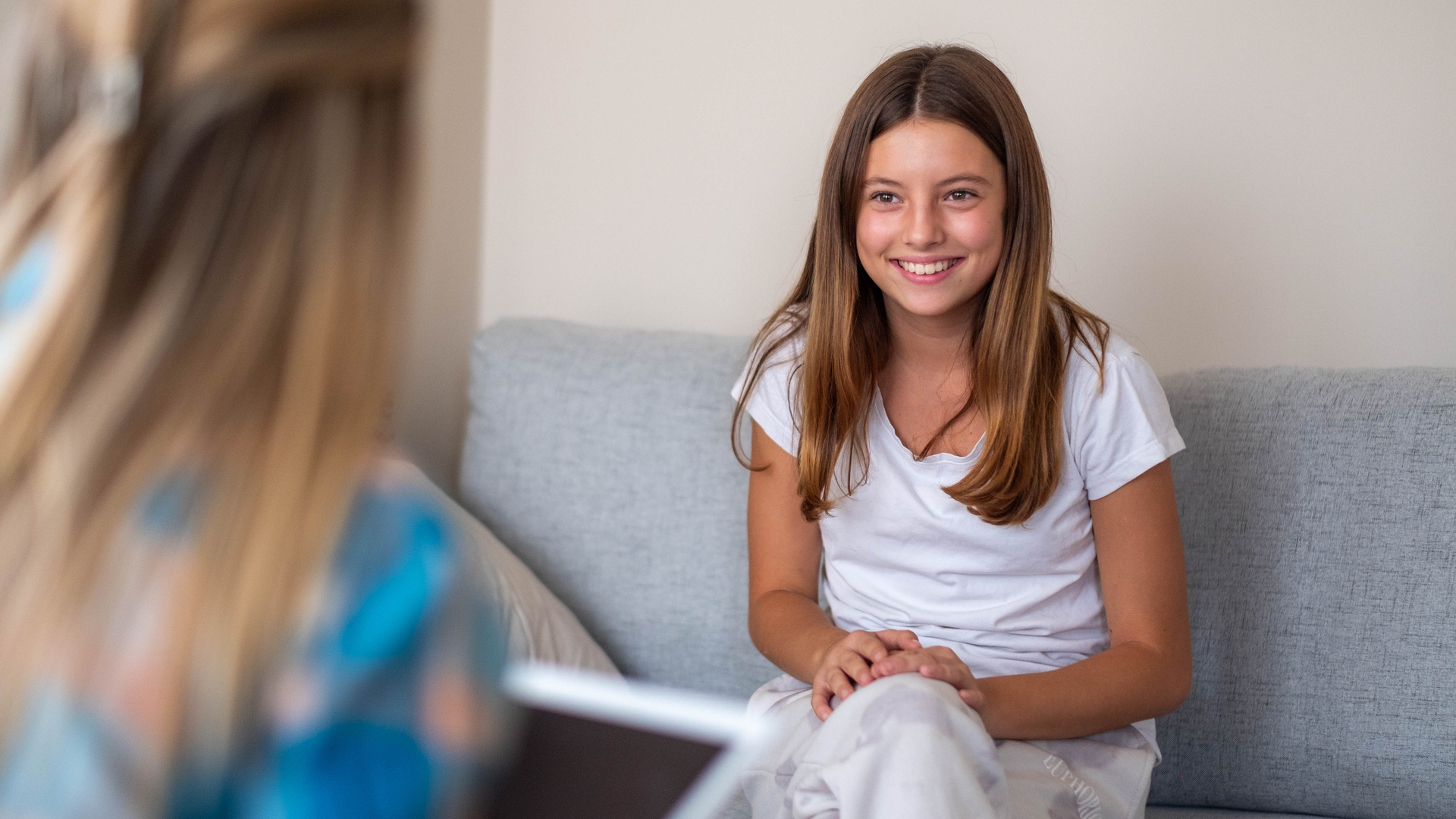 Young female teen sitting on a sofa discussing with a female psychologist during a counseling session
