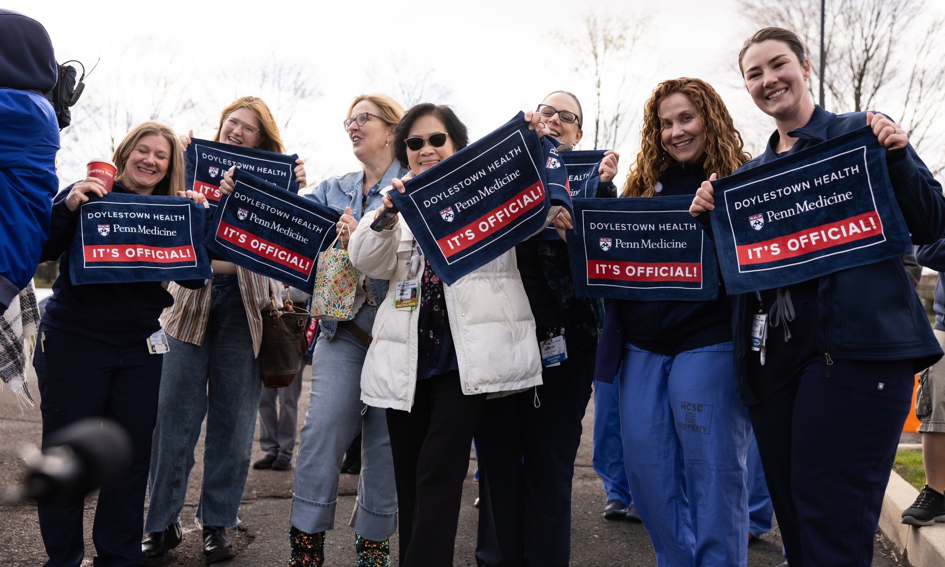Doylestown Health staff wave rally towels that say "Doylestown Health / Penn Medicine / It's Official!"