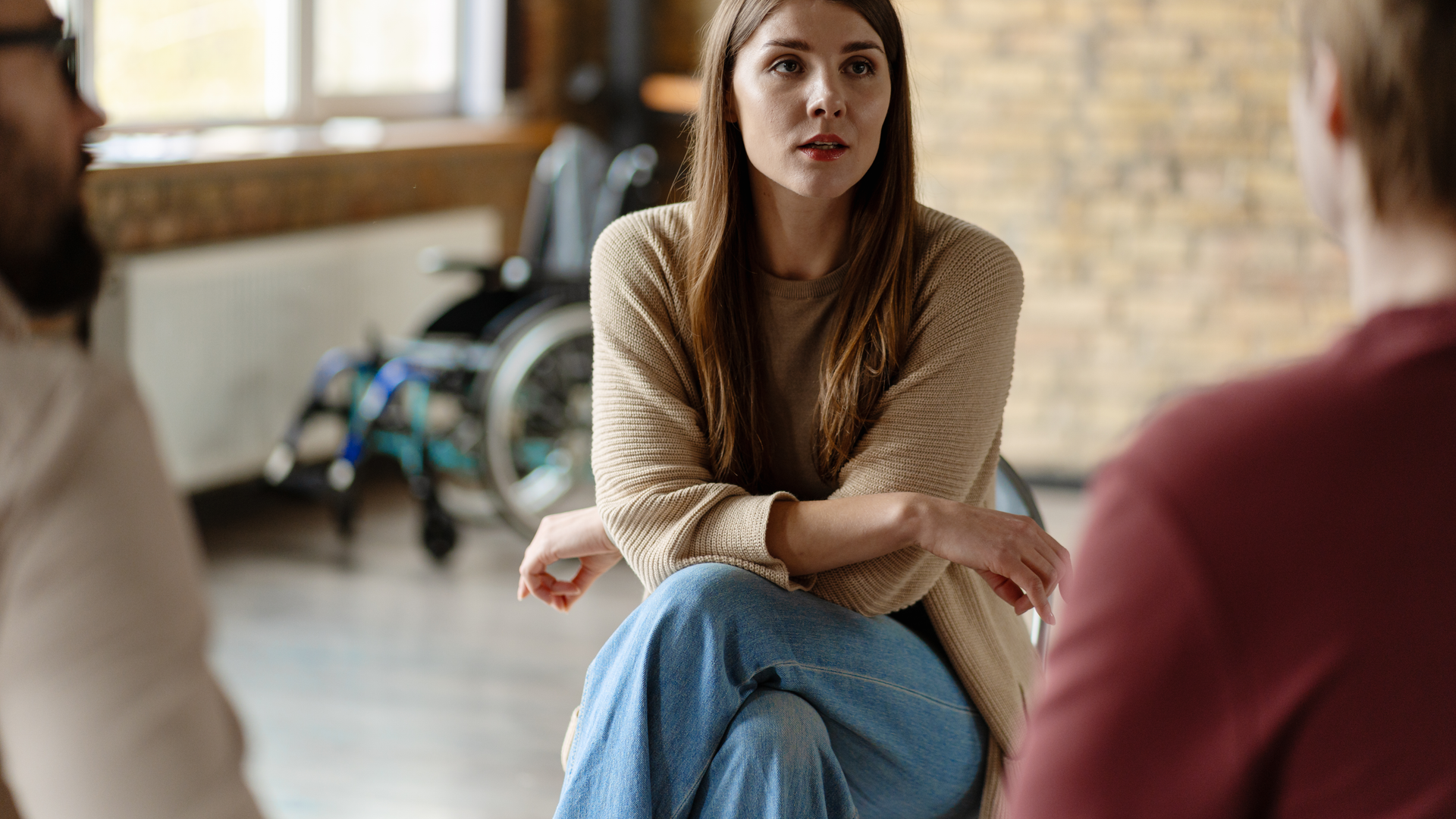 Young woman leading a group therapy session for people with disabilities, helping them to cope with their challenges and improve their mental health