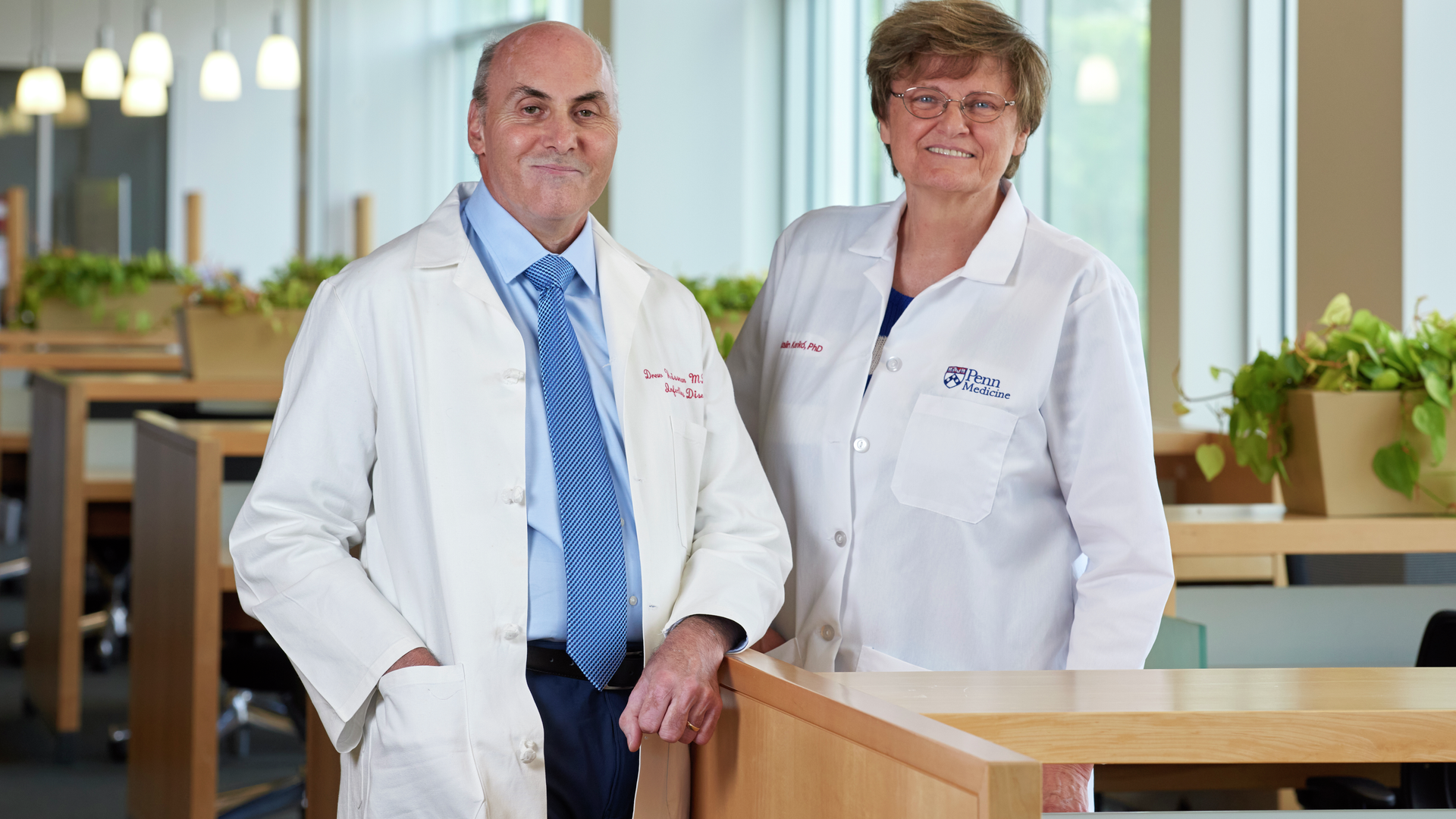 Drew Weissman and Katalin Kariko, smiling, wearing white coats