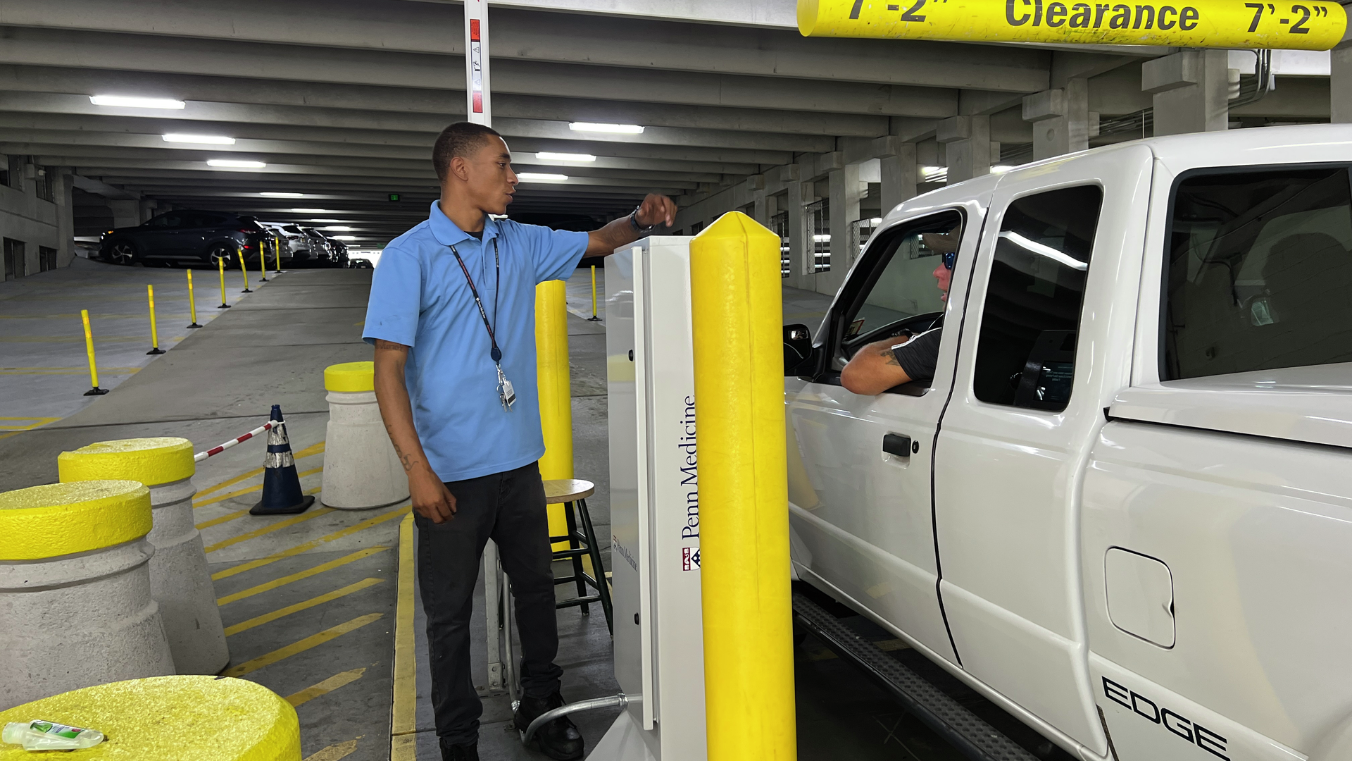 Parking garage greeter Tommy Barbieri stands by the ticket machine, chatting with a driver