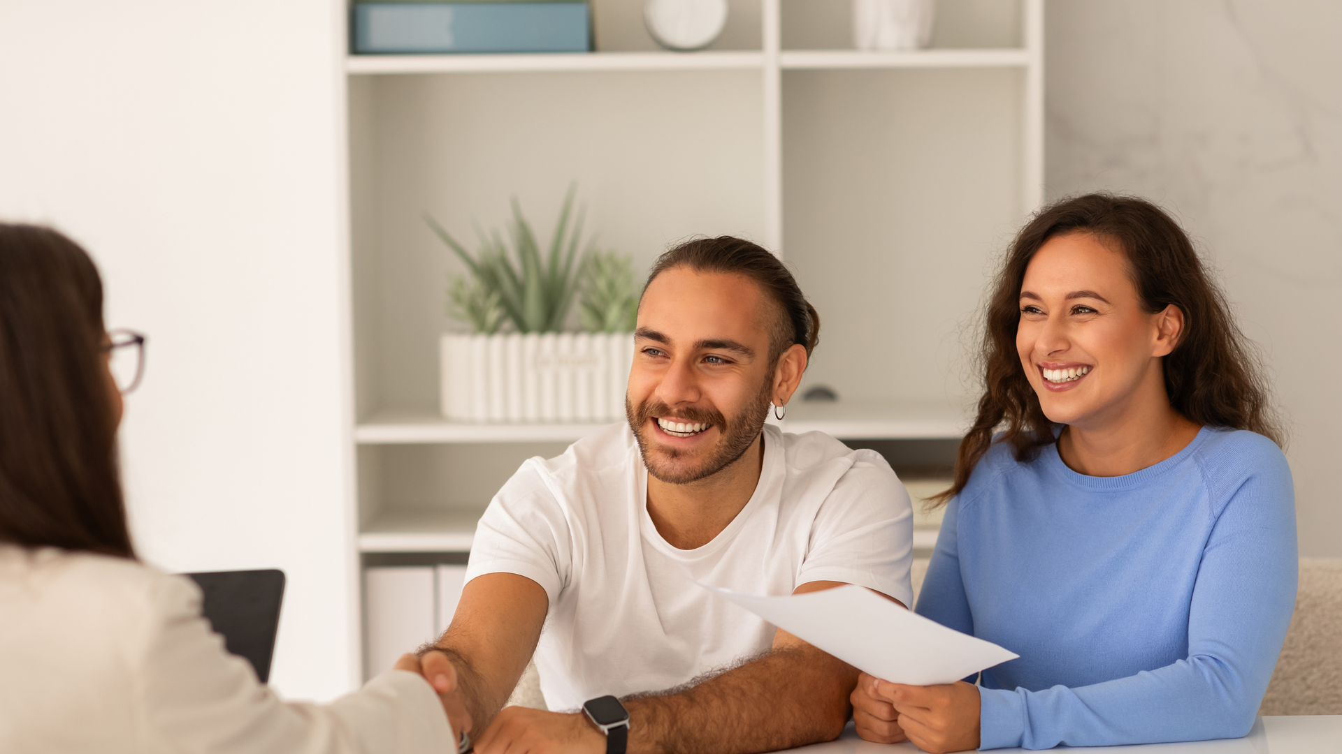 A couple is smiling while the man is shaking the doctor's hand