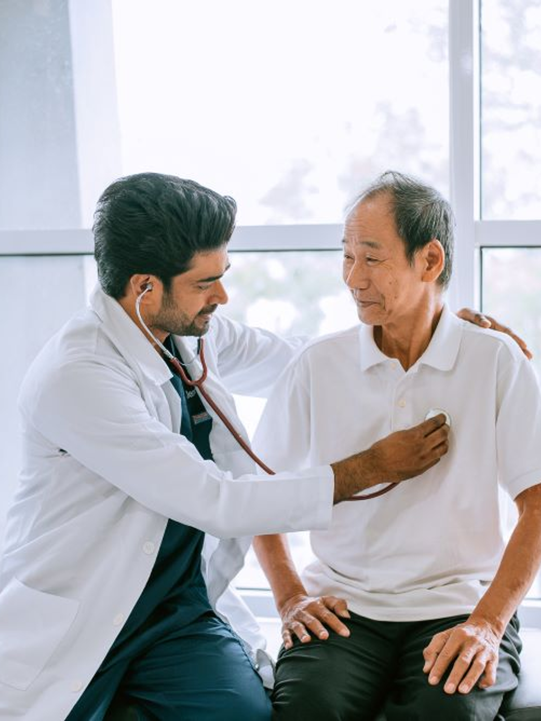 A physician applies a stethoscope to the chest of an older patient
