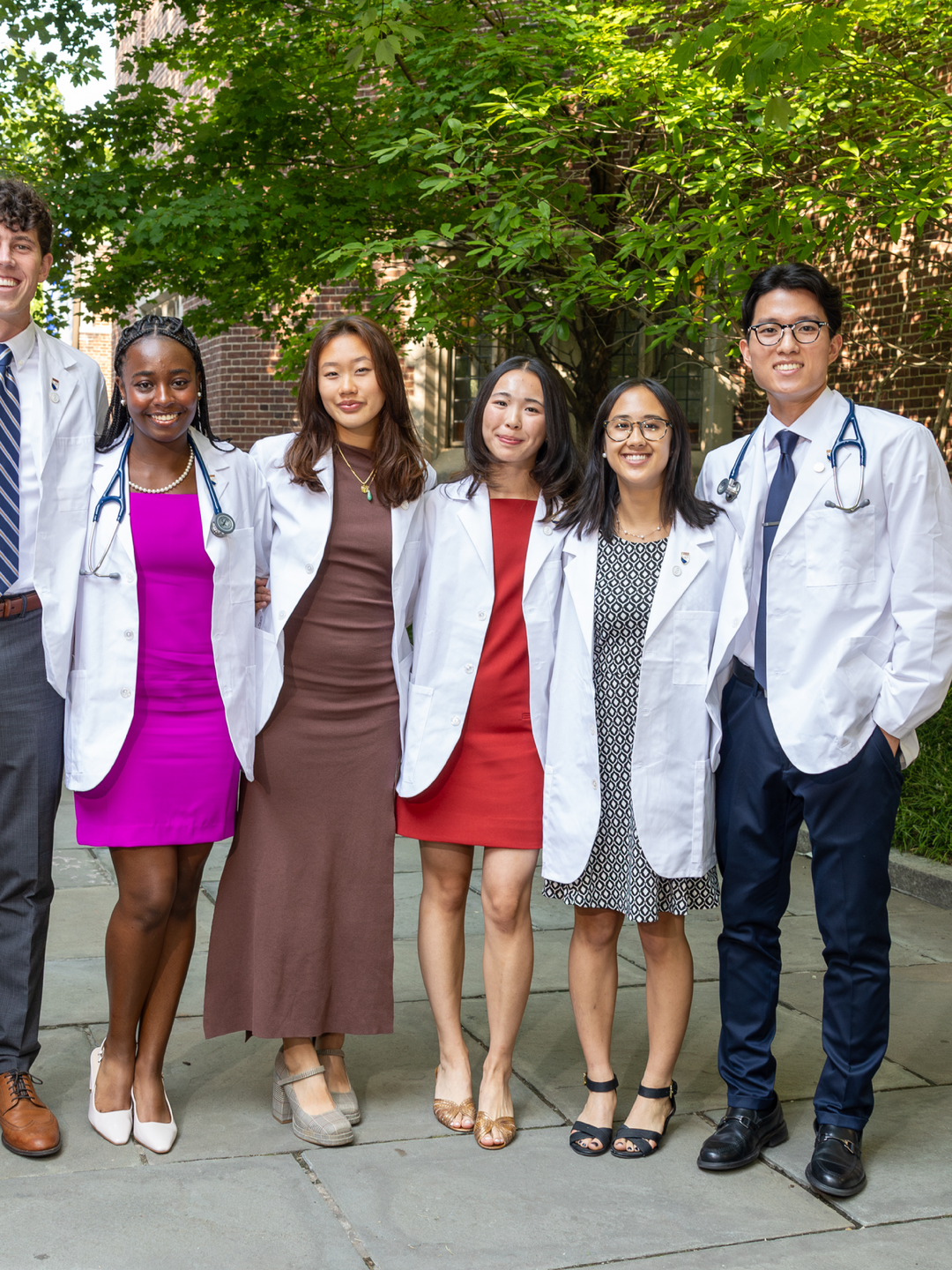 A group of students posing outside in their white coats