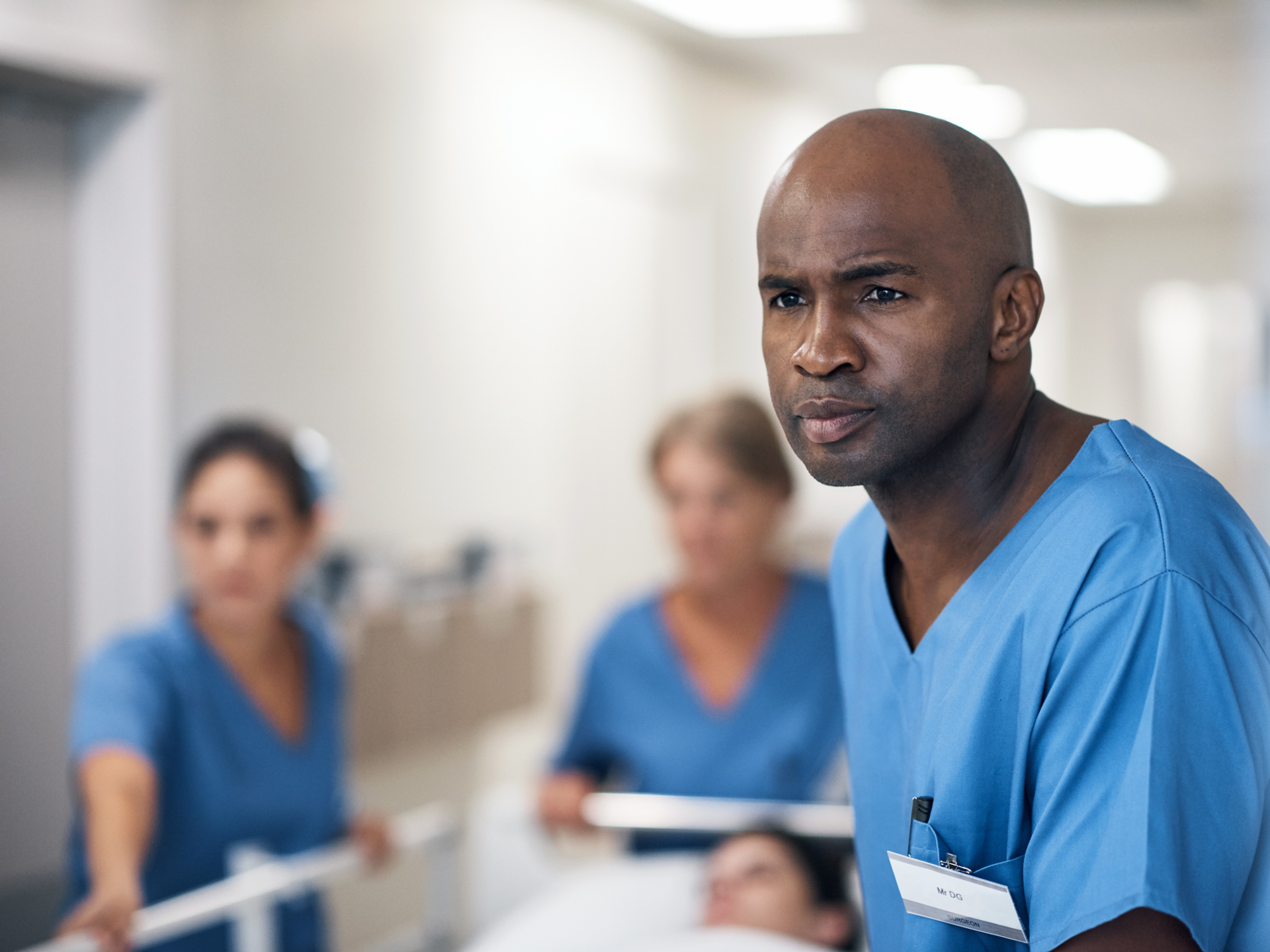 Cropped shot of a handsome mature male nurse and his team pushing a patient down the hallway in a gurney.