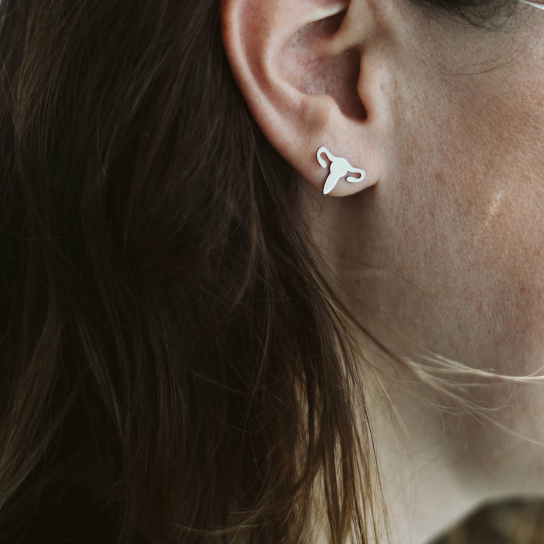 A close-up of a uterus-shaped earring