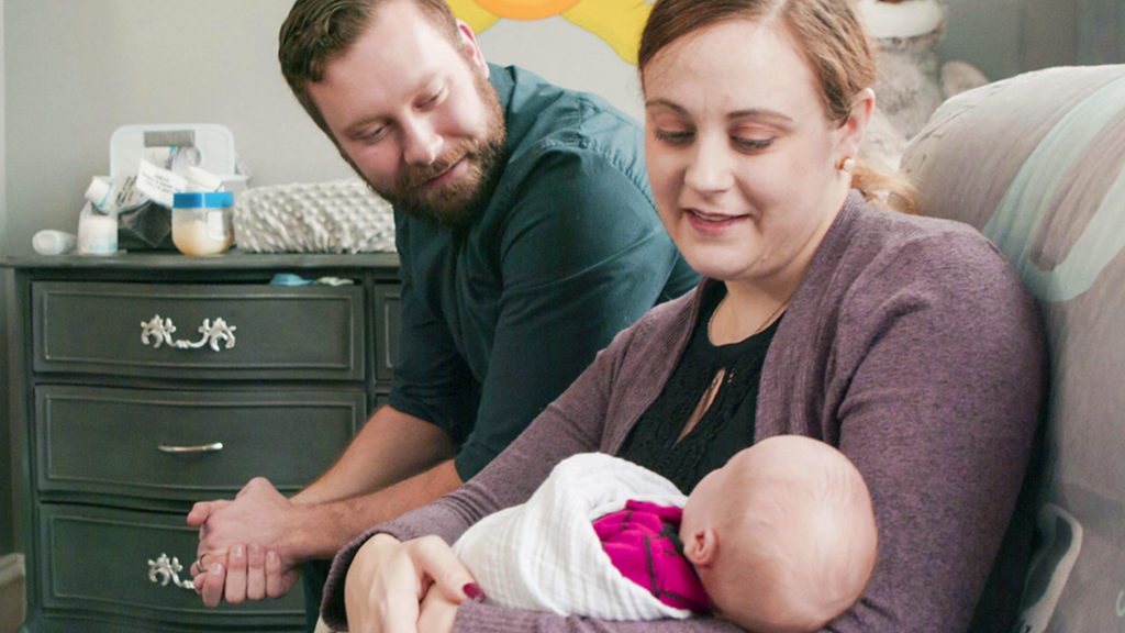 A couple with newborn infant are shown in maternity ward
