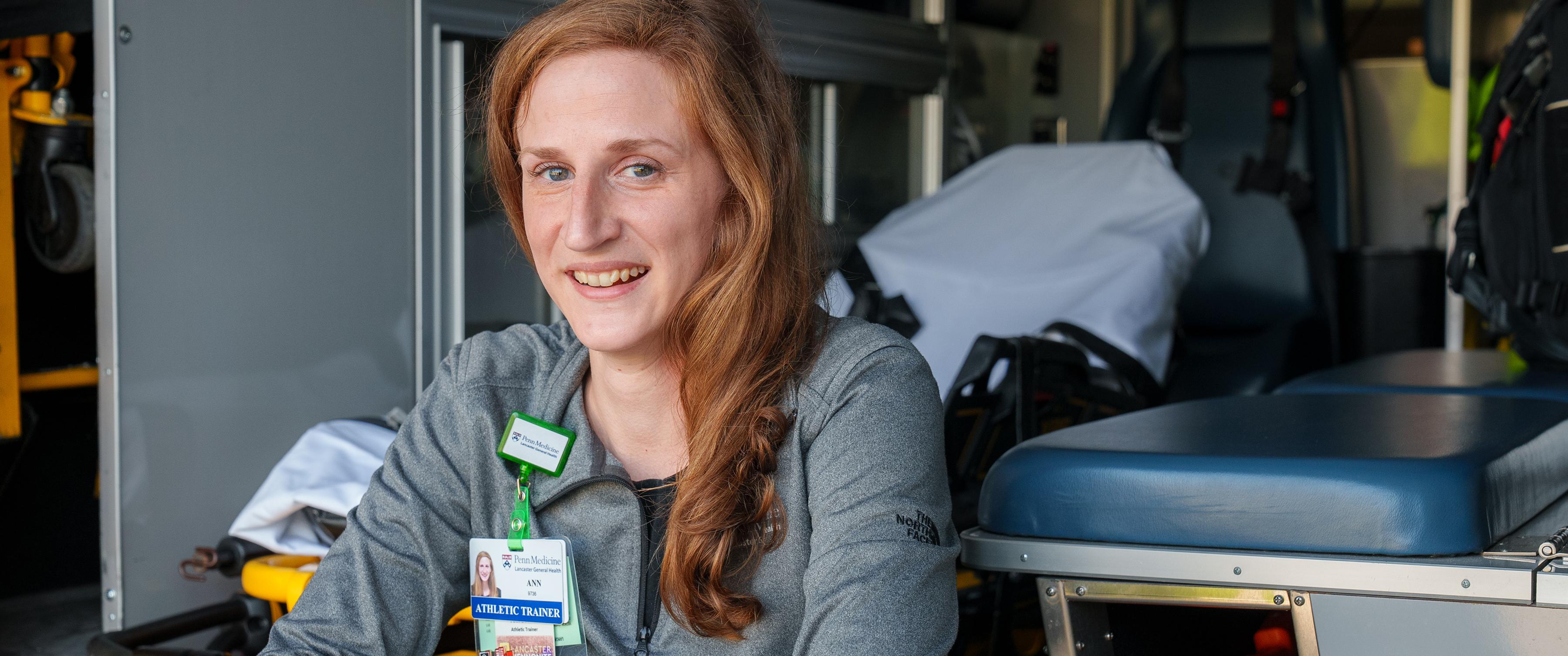 Ann Seaton smiles, sitting at the back of an ambulance, surrounded by EMS equipment