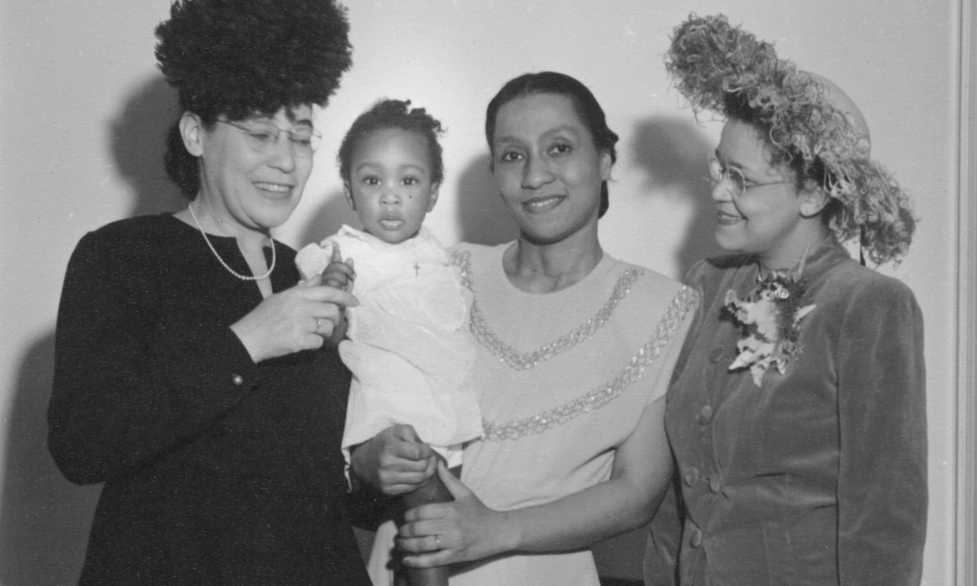 Dickens, a young woman wearing a sparkly dress, holds her young daughter Jayne, surrounded by Virginia Alexander, MD, and Sadie Tanner Mossell Alexander