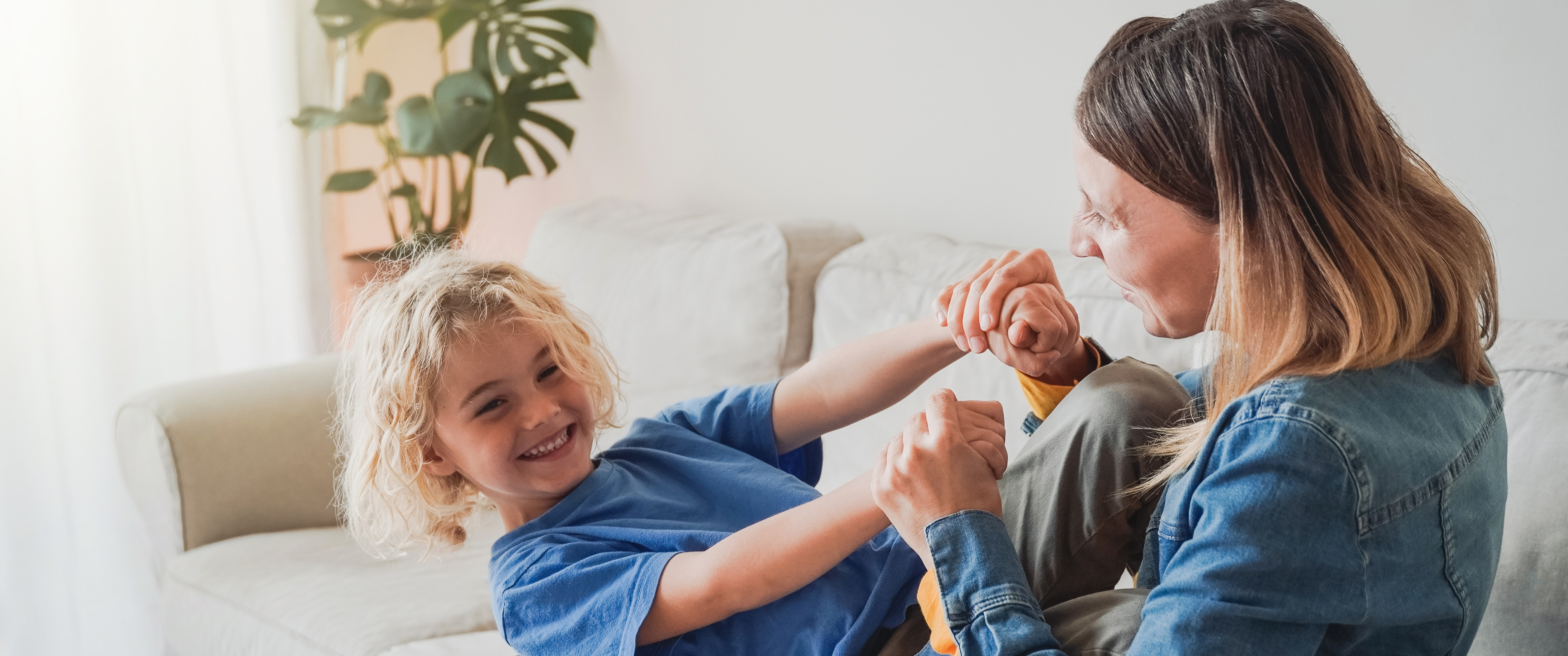 Mother hugging young boy on sofa