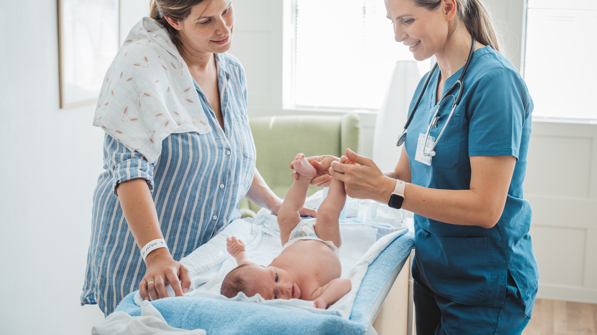 Pediatrician nurse checking baby and showing mother how to take care of baby.