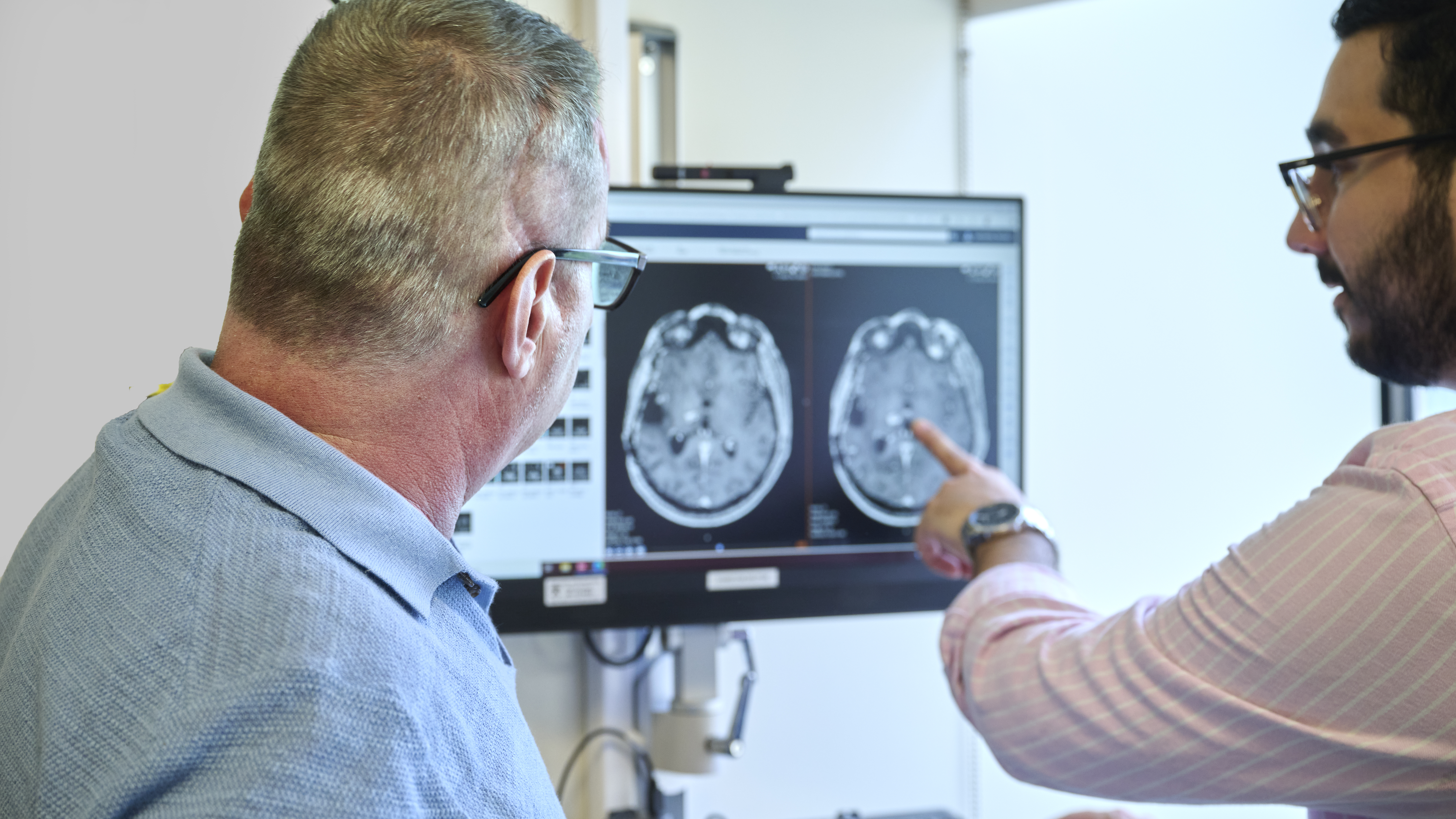 Nicolas Sarmiento pointing to MRI brain scan results for Eduart Cuka, who looks on