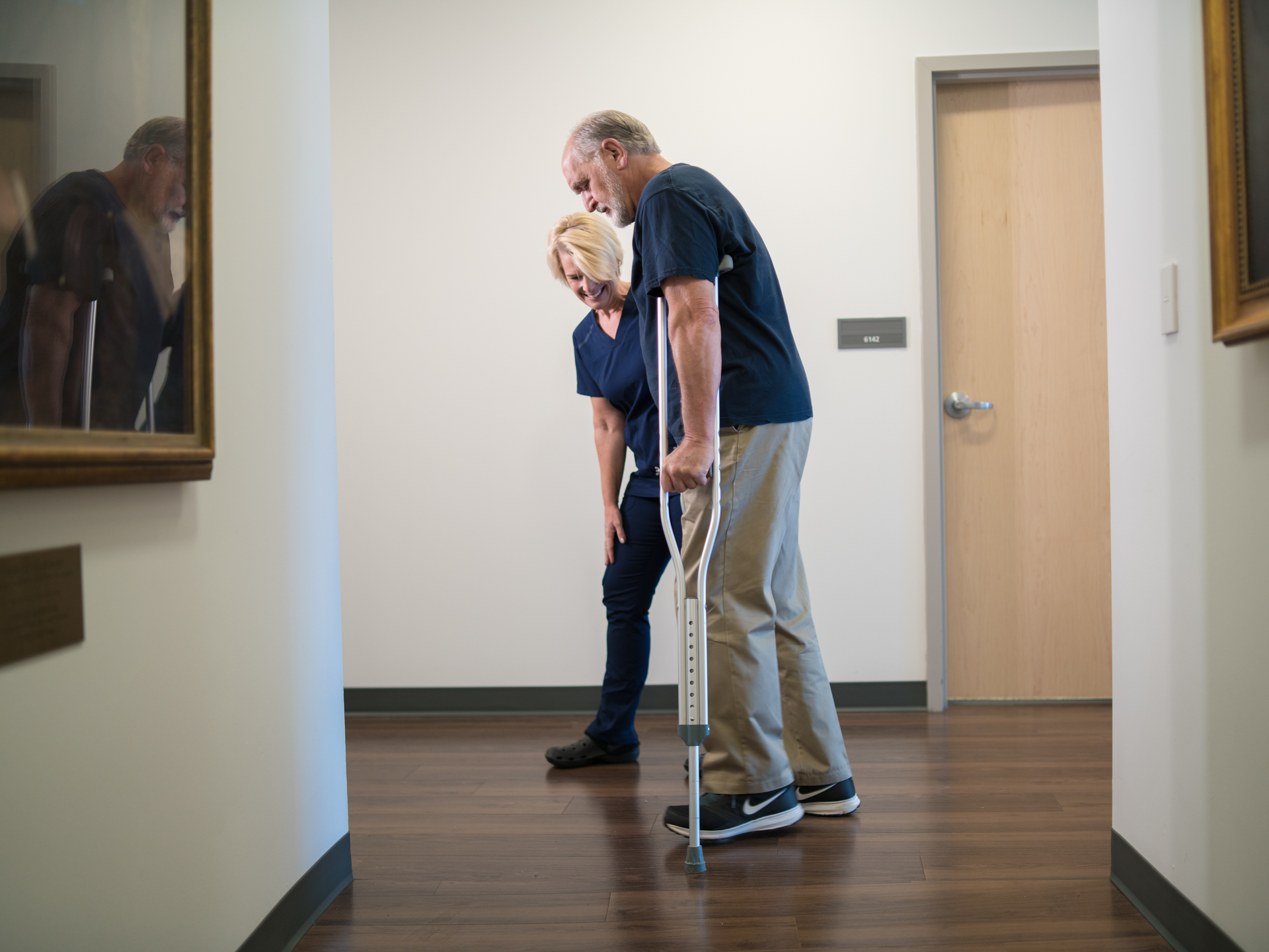 Nurse helps patient on crutches 