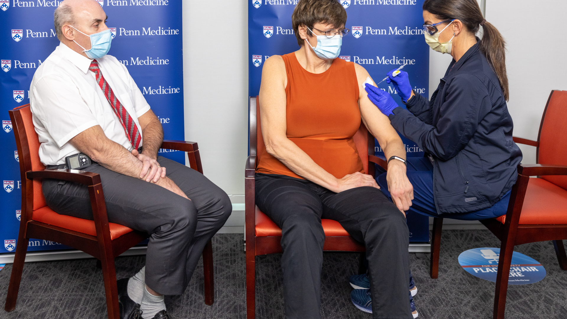 Drew Weissman watches as a medical professional injects an mRNA vaccine for COVID-19 into Katalin Karikó's upper arm