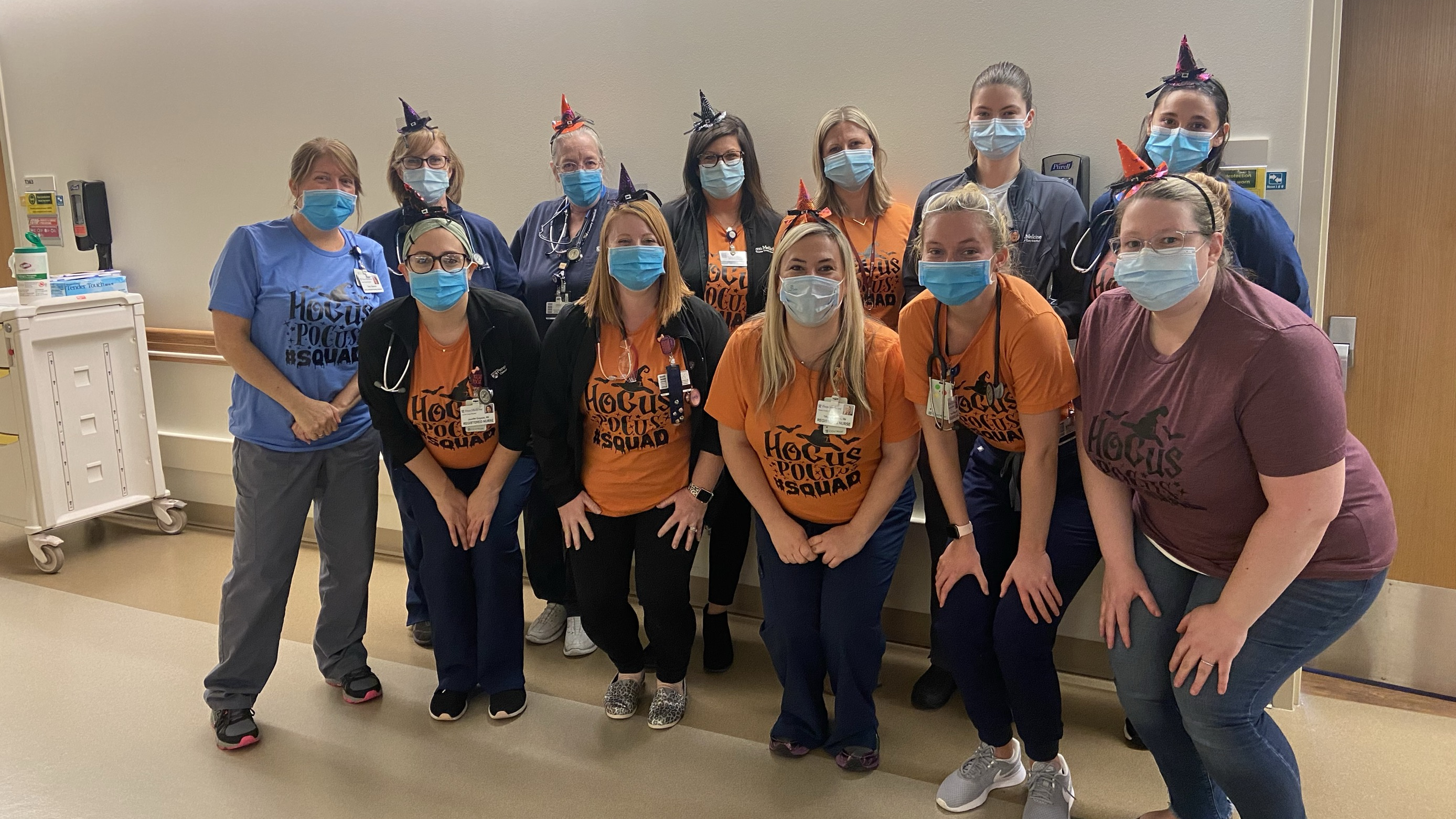 A group of nurses dressed in orange pumpkin shirts and small witch hats
