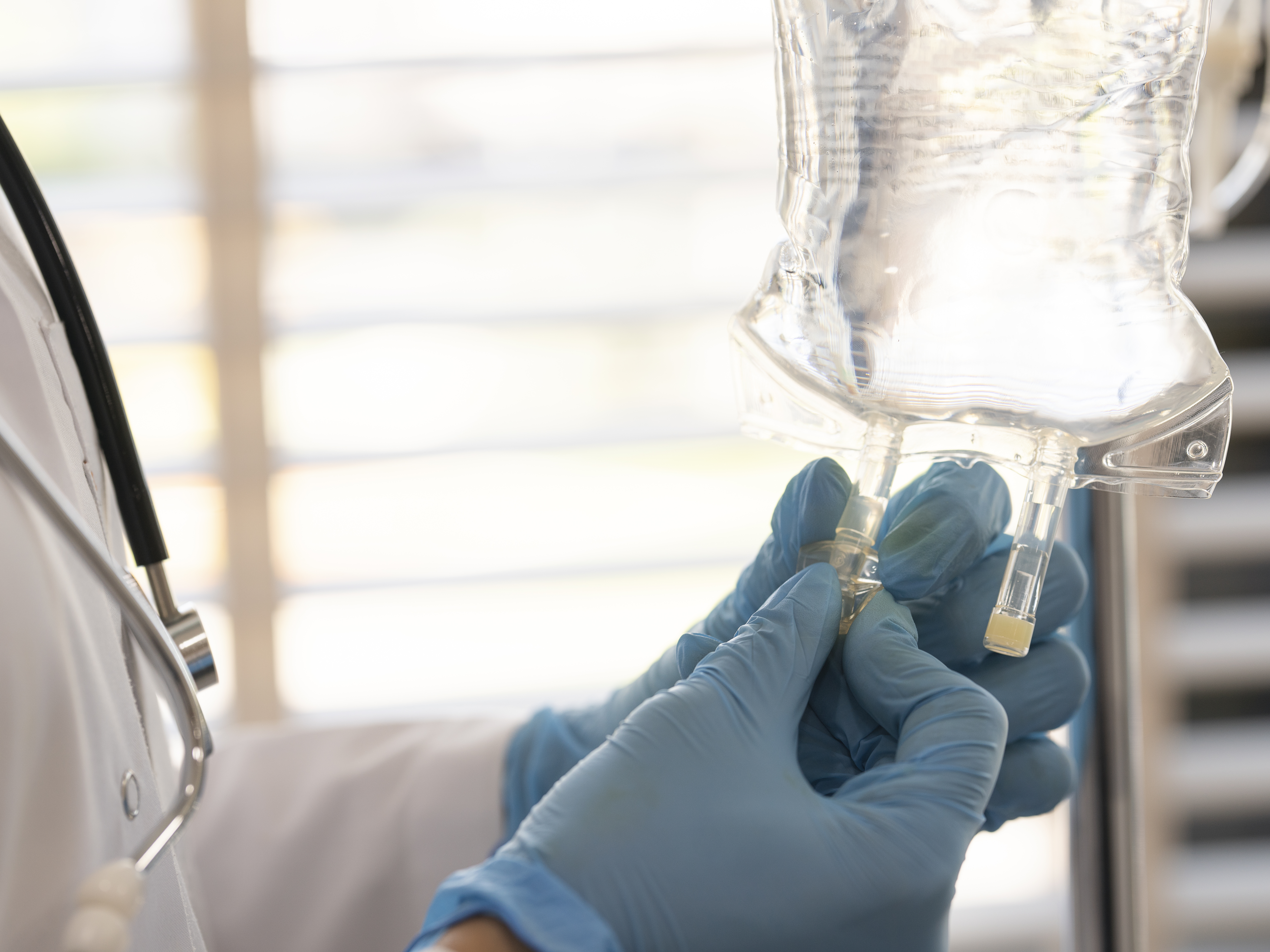 A medical personnel adjusting a tube on a saline bag.