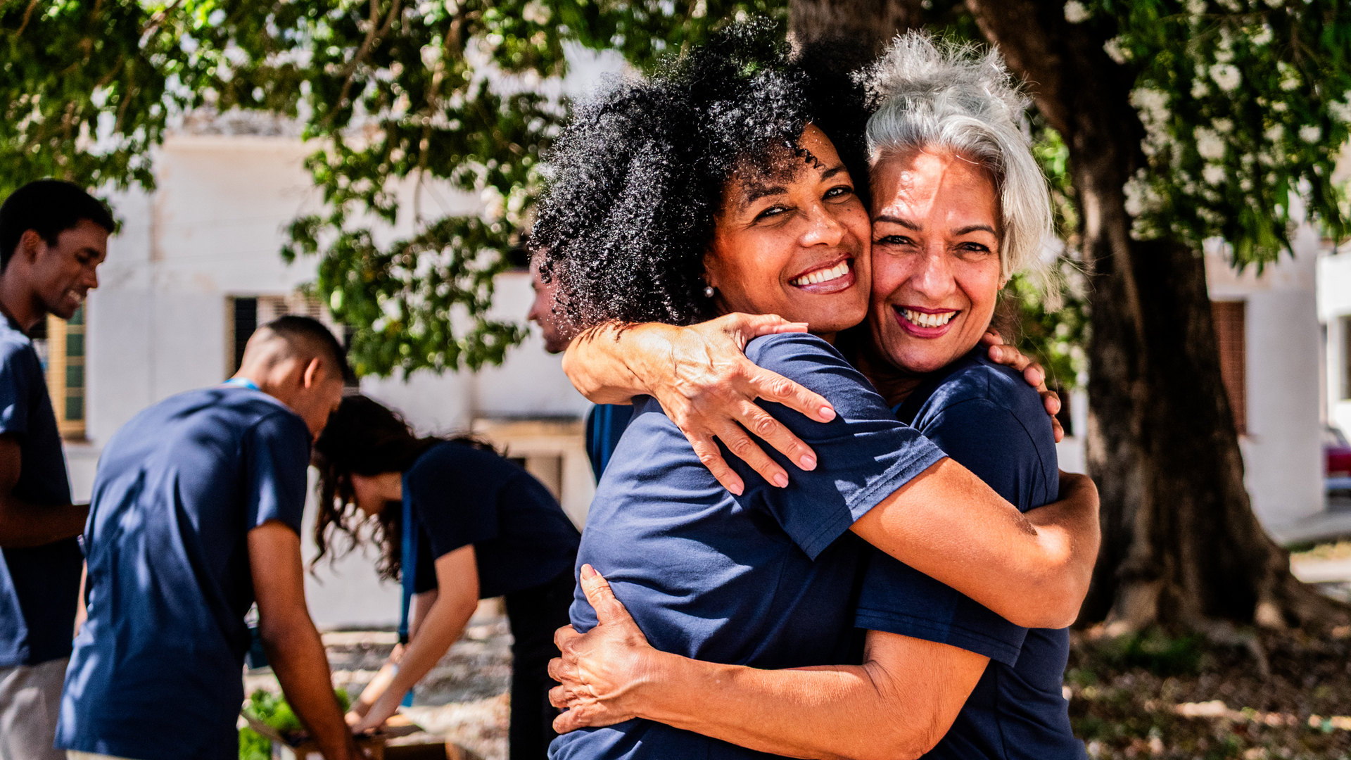 Portrait of volunteer friends embraced in outdoor settings.