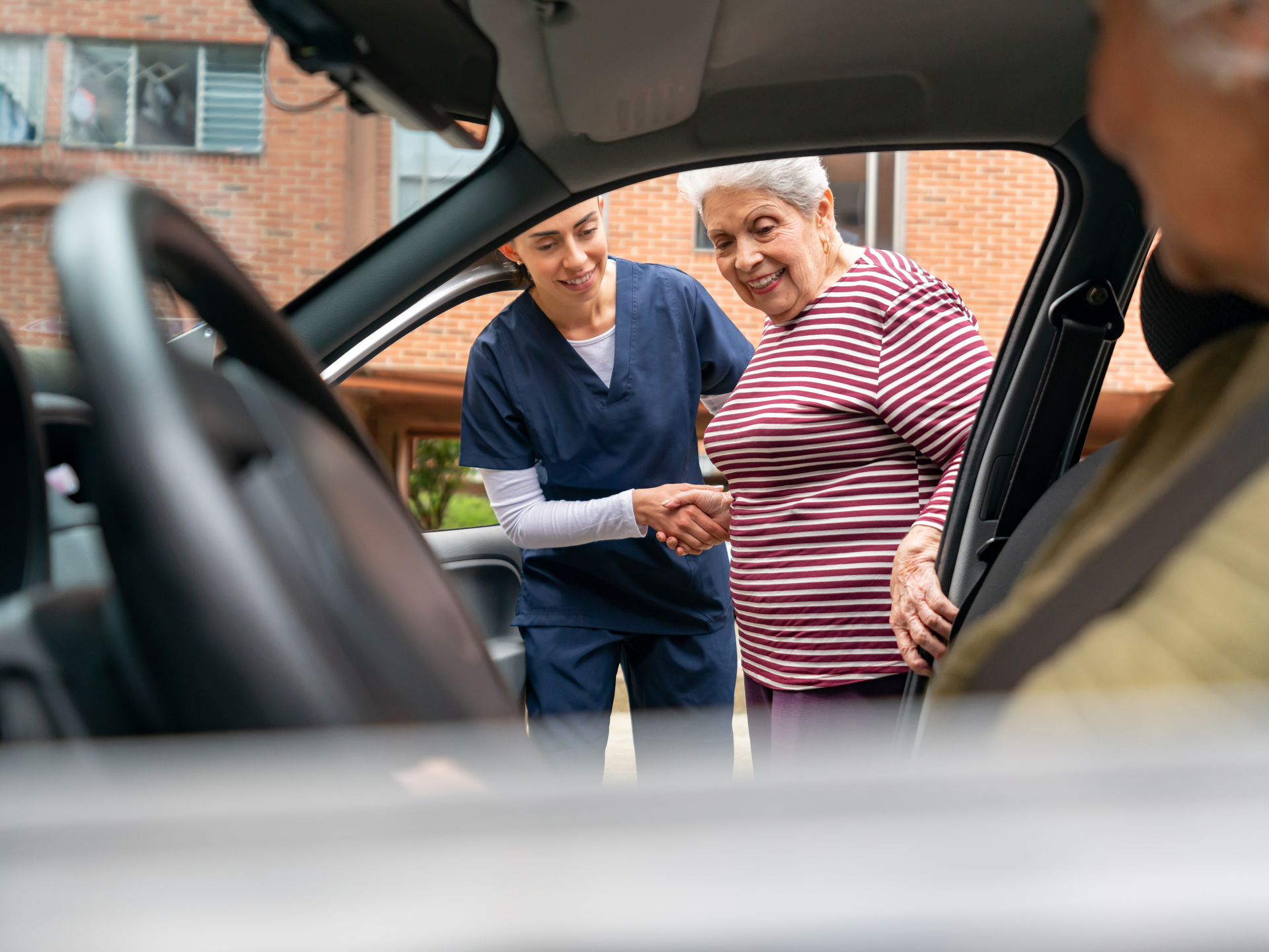 Home caregiver helping a senior woman get in a car