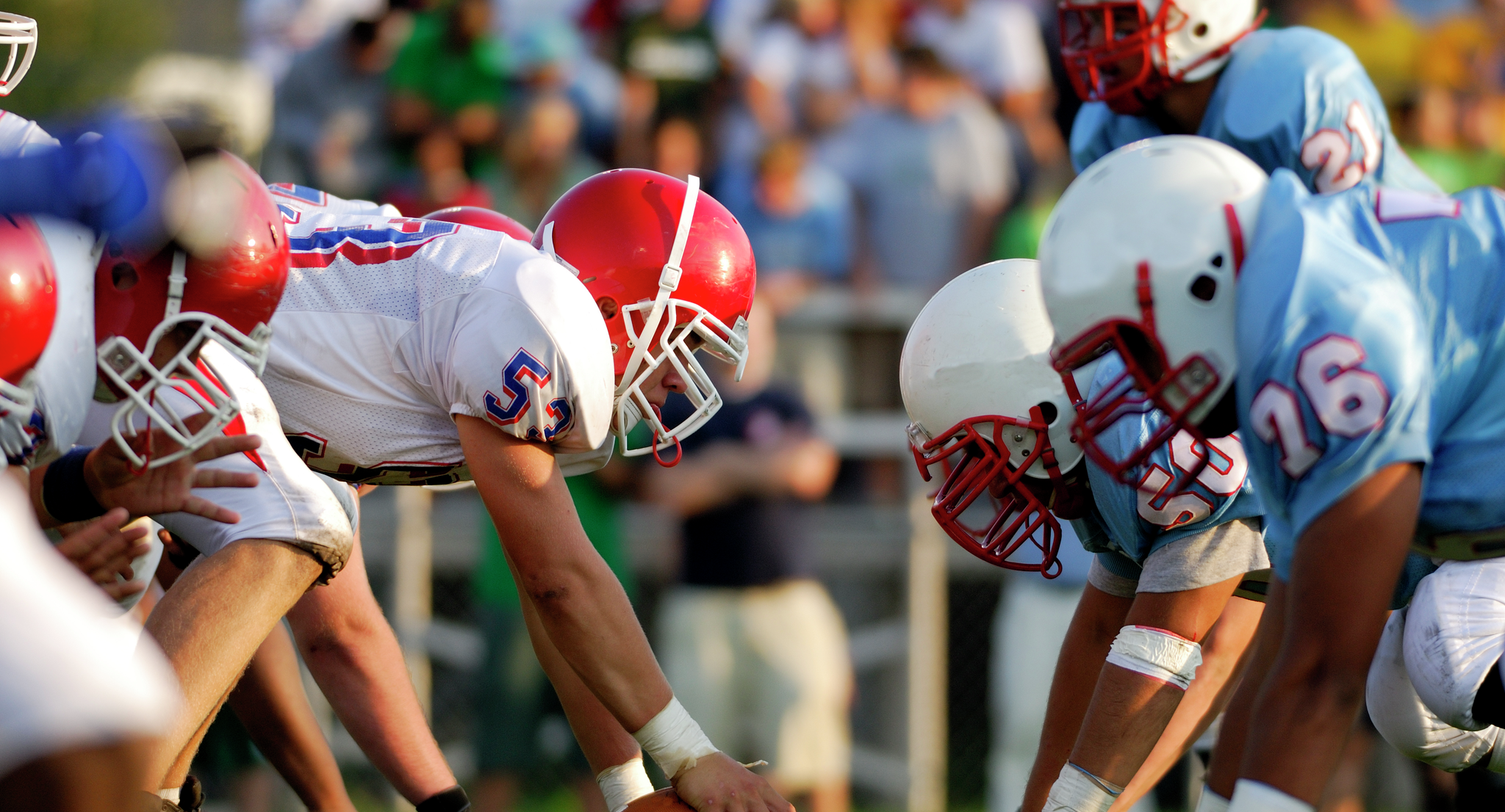 Youth football players wearing helmets in a line of scrimmage