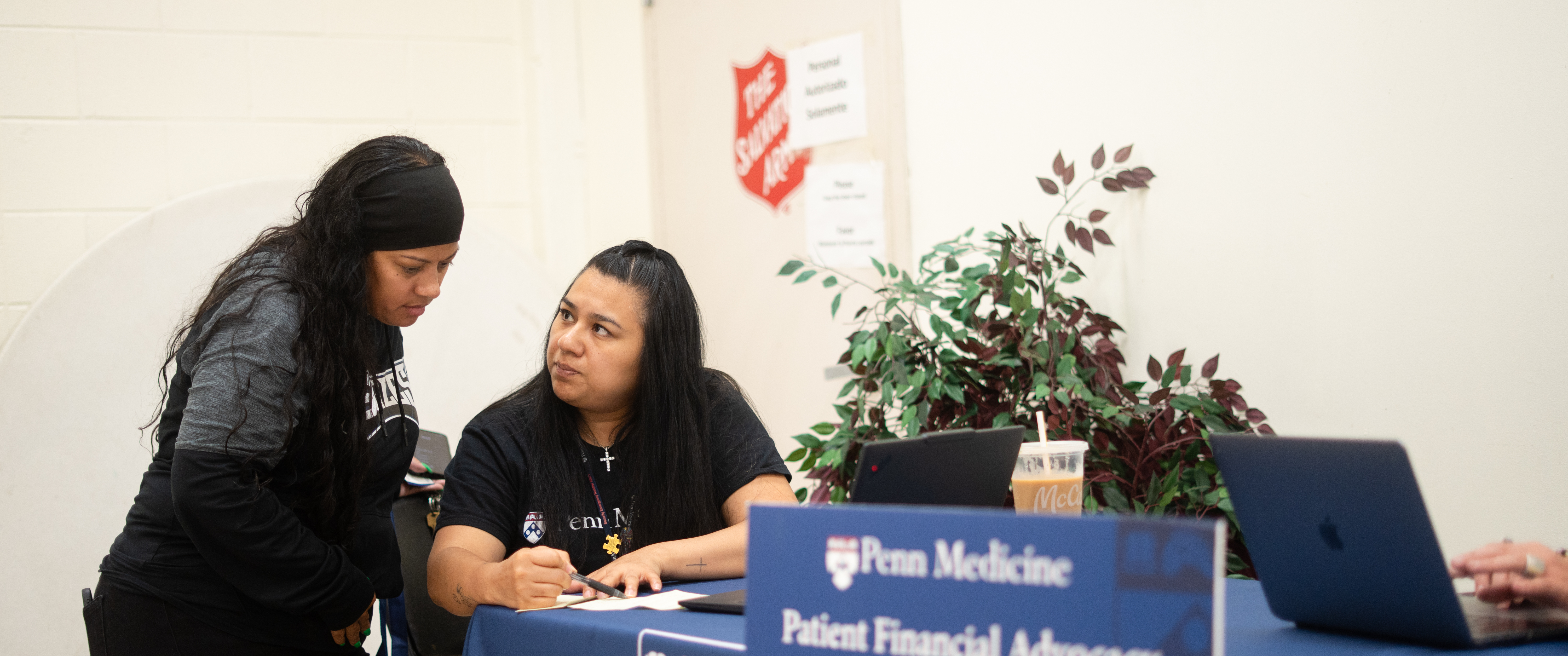 A Penn Medicine financial advocate speaks with a community member at an information table during an outreach event